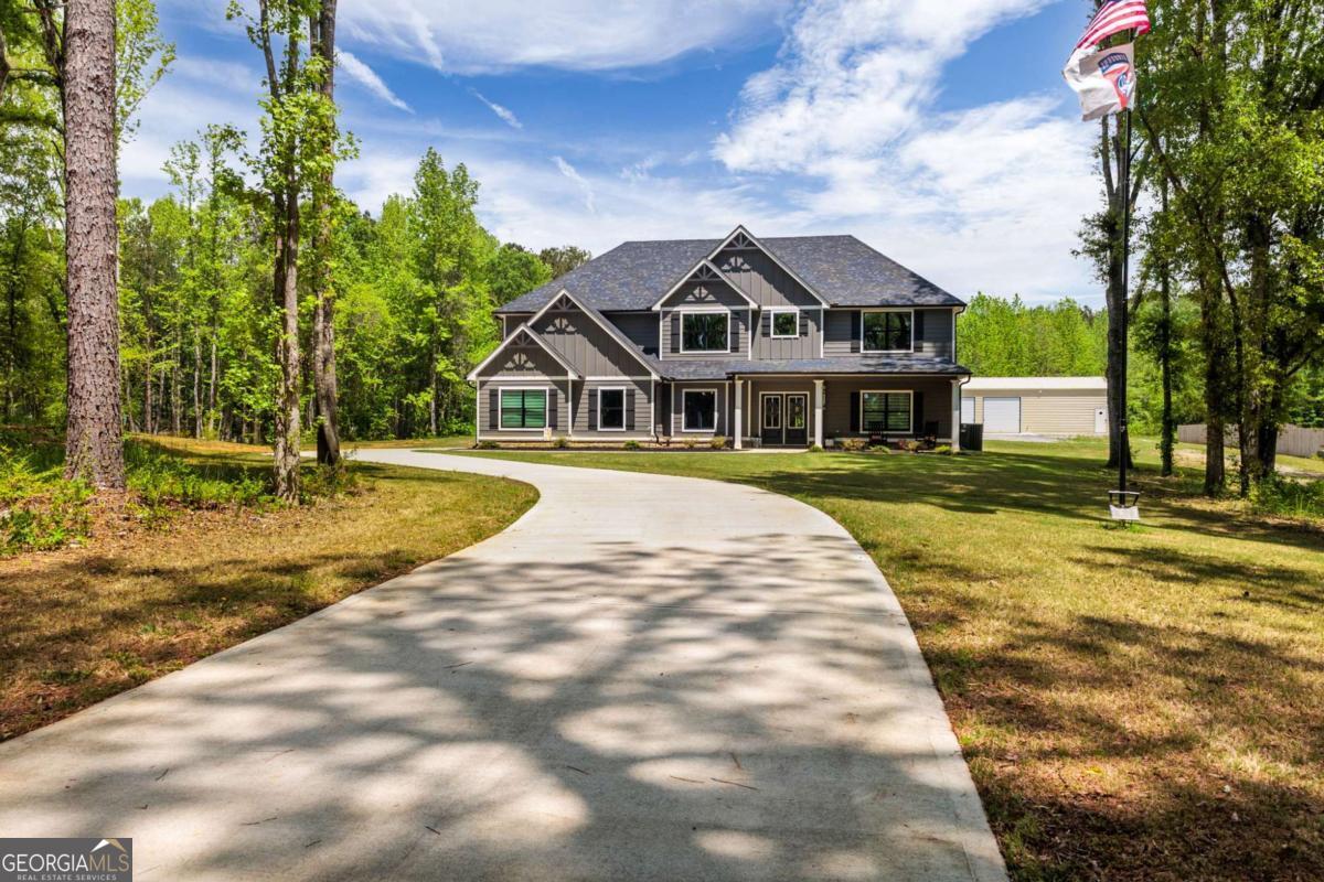 Discover this beautiful 2023-built home, perfectly located in the highly sought-after Sandhill-Hickory Level area of Carrollton, GA, offering a rare combination of modern living and serene country charm. Situated on 4.92 acres of fully usable land, this property provides the perfect setting for both relaxation and everyday convenience. Featuring 5 spacious bedrooms and 3.5 bathrooms, this home is ideal for growing families or those who love to entertain. The open-concept floor plan offers a seamless flow between the expansive living areas, while a versatile loft space provides additional flexibility for an office, playroom, or cozy den. The kitchen is a true highlight, open and spacious with abundant cabinetry, an oversized island with a breakfast bar, and a welcoming eat-in breakfast area. The luxurious primary suite is conveniently located on the main level, offering both privacy and comfort. Step outside and enjoy your morning coffee or evening relaxation from the covered front and rear porches while taking in the peaceful views of the surrounding nature. For those dreaming of a mini-farm, you'll love that fruit trees have already been planted, garden beds have been established, and a large chicken coop has been built, offering a wonderful head start toward your country-living goals. Adding even more value, the property features a 60' x 30' shop, fully insulated with spray foam, heated and cooled, and equipped with its own separate power meter perfect for hobbies, storage, or a small home-based business. A 13' x 60' shed has also been added to the back of the shop, providing even more outdoor storage space for equipment, tools, or farm supplies. This home delivers modern amenities, generous living space, and a rare move-in-ready opportunity with thoughtful upgrades already in place & features you won't typically find with new construction. Don't miss out on this true gem in the heart of the country!