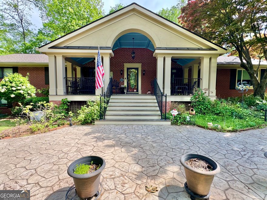 Welcome to the 431 Loop-Where Charm, Craftsmanship, and Comfort Converge on 1.11 Glorious Acres.     Nestled in a coveted neighborhood, this unforgettable Southern beauty invites you in with its grand, Brazilian hardwood rocking chair front porch-an ideal place to sip morning coffee or greet neighbors in true front-porch fashion. Winding around the home is a charming river stone sidewalk lovingly known as "The 431 Loop," setting the stage for strolls through manicured gardens bursting with perennials, mature Japanese maples, blooming jasmine along the fence line,  gardenias,  blooming hydrangeas, and many other perennials offering beauty in every season. This is not just a home-it's a sanctuary for gardeners, dreamers, and those who crave a deep connection with nature.    Step through the front door into a home where timeless quality meets thoughtful design. You'll find a formal living room and dining room, perfect for holiday gatherings and quiet dinners alike. The heart of the home-the eat-in kitchen-flows into a spacious family room that opens into a sun-drenched sunroom wrapped in UV-blocking glass. Here, you'll find serenity in every season, whether curled up with a book or watching goldfish dance in the backyard pond.    The kitchen is a chef's delight with a gas cooktop and instant hot water from the gas water heater. For grill enthusiasts, there's a gas line to the deck, making outdoor cooking effortless. Just off the sunroom, two decks overlook a backyard oasis with a waterfall-fed pond, and a forested backdrop that offers beauty and privacy year-round.    On the main floor you'll find four generously sized bedrooms, including a handicap-accessible primary suite with double closets and a built-in safe. Downstairs, the finished basement space is more than just bonus space-it's a retreat. It features a cozy living area with a wood-burning stove, a library or office with built-in bookshelves, a spacious bedroom with an en suite bathroom, and its own private entrance. Notably, this was once the residence of the first pastor of the First Baptist Church, adding a layer of local history and warmth.    Need storage? There's a two-car garage, an additional parking pad, a dedicated storage shed, and a separate woodshed just outside the basement-perfect for fueling your fireside nights.     You'll appreciate features like a central vacuum system, 6-inch gutters with leaf guards, and an attic built with sturdy antique redwood, which speaks to the quality and craftsmanship that runs throughout this remarkable home.    This property is more than a residence-it's a lifestyle. From the sunlit front yard to the wooded backyard, from its rich history to modern conveniences, every inch of this home has been lovingly curated for comfort, beauty, and functionality.    Come experience the magic of the 431 Loop-Omni's Garden located conveniently to Kennestone Hospital, Interstate 75, and the Marietta Square. Homes like this don't come along often.