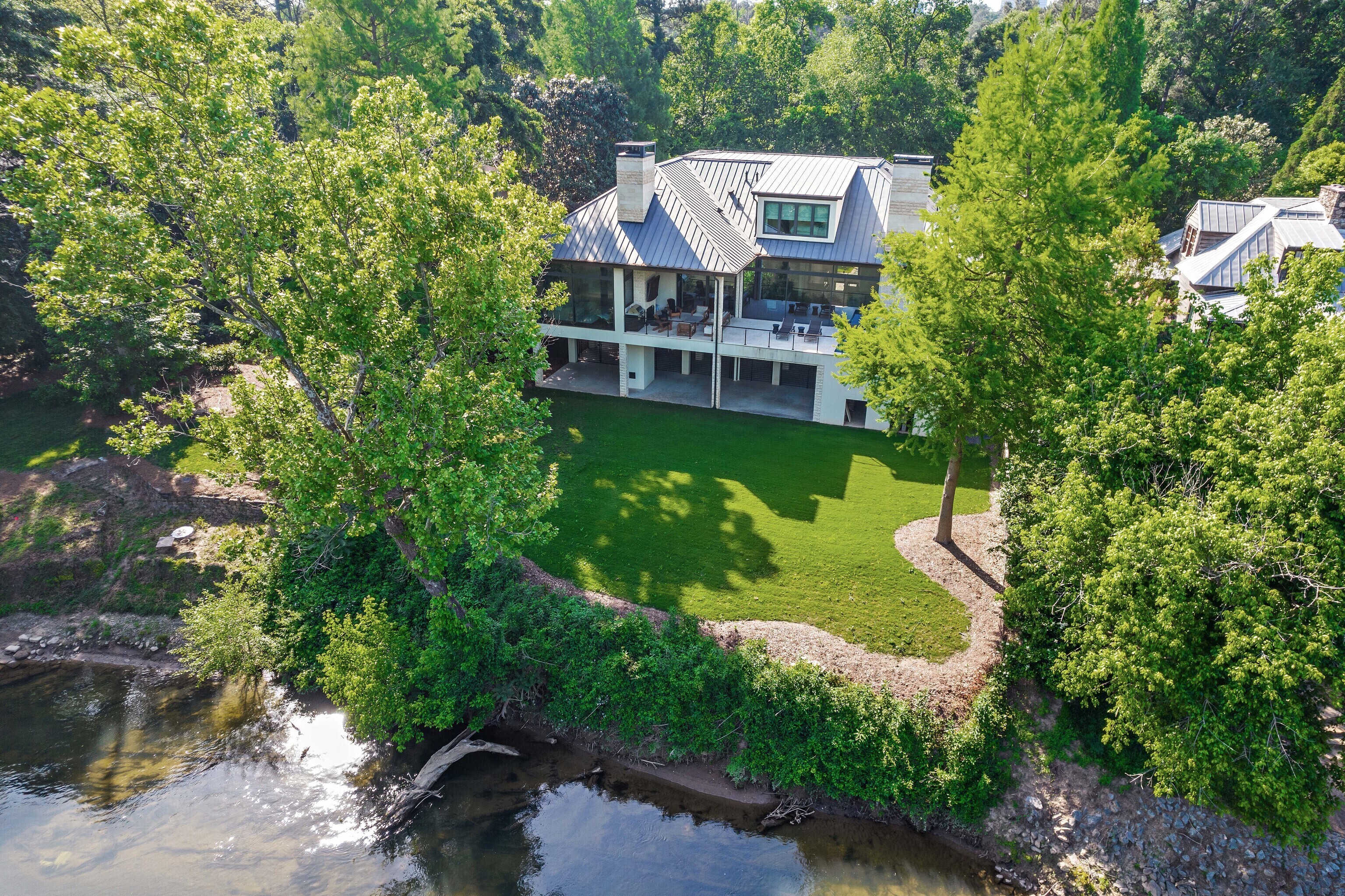 3979 West Paces Ferry is an unsurpassed estate set majestically on the Chattahoochee River in AtlantaCOs exclusive Buckhead neighborhood. Construction was completed in 2020 and one of the last homes constructed with a fifty-foot set back from the river. The home illustrates uncompromising constructions methods Co over 110 helical piers and four feet of concrete.The ground floor garage features room for ten cars through three separate entry doors.Enjoy the serene views of the Chattahoochee River while relaxing in the outdoor entertainment space with a wall mounted flat screen over the fireplace or unwind in the pool or sauna located on the spacious second floor patio. Inside the open floor plan, experience panoramic views and natural light via the floor to ceiling. Twelve foot ceiling heights throughout the main living area provide a spectacular feeling of space. privacy glass. Perfect for entertaining, the kitchen features a Miele microwave, convection, and coffee maker plus two subzero refrigerators and double size wolf range with large stainless vent. The kitchen and bar area also come complete with ice maker, wine fridge and multiple chilling drawers. The master suite is located on the main living floor and features a spacious sitting area with fireplace and floor to ceiling privacy glass with amazing views of the river. With the press of a button, lower your privacy screen and black out the room for a perfect nightCOs sleep. The master bath is expansive with his and hers vanities, enormous shower and sandstone soaking tub. Turn on the whole house entertainment system and listen to your favorite music as you soak in this one of kind tub. Additional spaces on the 2nd floor include guest rooms, laundry and the office complete the second floor living area. Access the elevator to the third-floor suite offering a private living space ideal for guests or extended family members. This suite features a full kitchen, bathroom, and beautiful sleeping area with river views. Other third floor spaces include a fitness/chill room. All mechanical systems including HVAC and whole house generator been raised twelve feet off the ground. The garage has space for ten vehicles and front lot can also accommodate another seven. The home is located 3/10's of a mile from Loveett School and very close to Westminster and Pace. This estate is a riverfront masterpiece and one-of-a-kind opportunity.