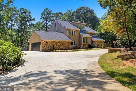 Stunning lakefront single-family residence at 3680 Lamplighter Cove Road, showcasing a beautifully renovated exterior with stone accents and a spacious driveway, surrounded by lush greenery in Gainesville, GA.