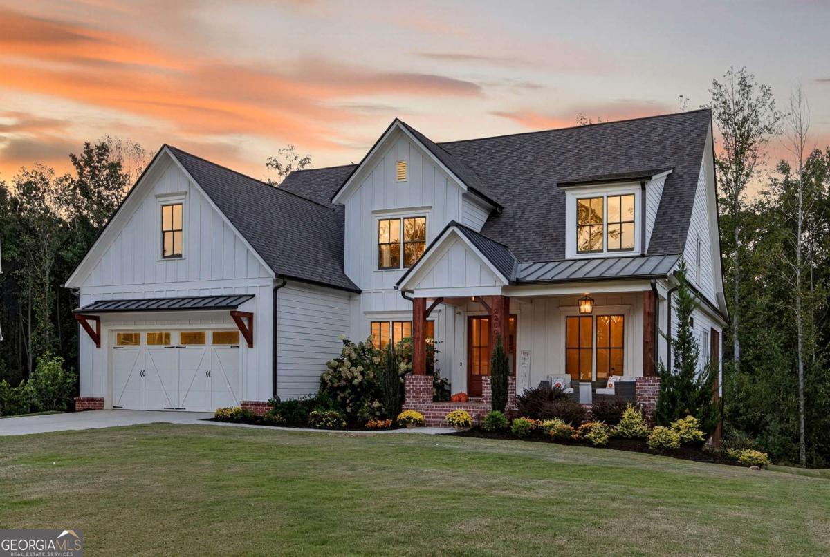 Crafted by esteemed builder Bercher Homes, this residence showcases the highly coveted Evans floor plan - one of West Cobb's most sought-after designs. Perfectly positioned at the end of a quiet cul-de-sac and framed by untouched natural landscape, the home offers rare privacy, timeless elegance, and an inviting sense of tranquility. Upon entry, the grandeur of the two-story family room immediately captivates, where 20-foot ceilings rise above a dramatic two-story wood-burning fireplace. A Juliet balcony from the loft overlooks this magnificent space, while 10-foot ceilings on the main level and 9-foot ceilings upstairs enhance the sense of scale and light throughout. At the heart of the home, a chef's kitchen is equipped with a five-burner gas cooktop and an expansive 10-foot island that flows seamlessly into the family room. Walls of windows frame sweeping views of treetops and the surrounding natural landscape, creating a serene backdrop for everyday living and entertaining. The main level is anchored by a refined owner's suite, complete with a custom boutique-style closet measuring 108 inches wide by nearly 18 feet deep - a retreat as functional as it is luxurious. From the suite, step out to a screened porch and oversized deck, where nature becomes a private extension of your living space. The breakfast area offers a daily connection to the outdoors, with views of lush greenery and the glimmer of the lake beyond. Upstairs, three spacious bedrooms with en-suite access and generous walk-in closets are joined by a versatile loft space overlooking the family room. Below, a 2,500+ square foot unfinished basement presents a rare opportunity to create a bespoke retreat, whether envisioned as a wellness sanctuary, wine cellar, or home theater. Practical modernity is seamlessly woven in with an electric vehicle charging station already installed in the garage. The lifestyle extends gracefully beyond the home itself. The community offers thoughtful amenities - including a pool, pickleball and tennis courts, clubhouse, and twin lakes for fishing and canoeing - all positioned nearby to preserve the home's privacy while enhancing an active and social way of life. Two private walking trails begin just beyond the property, connecting you effortlessly to nature. Located in desirable West Cobb, this home is just seven minutes from vibrant Marietta Square, with its abundance of dining, boutiques, and community events. Historic Kennesaw Mountain offers trails steeped in history and natural beauty, while premier private schools - Mount Paran Christian (7 minutes), The Walker School (16 minutes), and North Cobb Christian (22 minutes) - are within easy reach. Kennestone Hospital is also minutes away, providing peace of mind. This is more than a home; it is a statement of refined living - where architectural beauty, modern convenience, and natural tranquility converge in perfect balance.