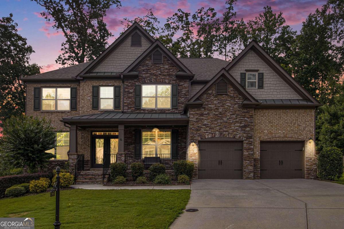 Elegant Executive Home in Sought-After Cul-De-Sac Location Space, style, and serenity converge in this stunning executive home nestled at the end of a quiet cul-de-sac. A charming rocking chair front porch and elegant double-door entry set the stage for what awaits inside. Step into the expansive great room, where soaring ceilings and a dramatic wall of windows-draped in custom 20-foot panels-fill the space with natural light. A stately stone fireplace flanked by built-ins creates the perfect focal point. The formal dining room impresses with a designer ceiling and ample space to comfortably seat 10+. A versatile flex room makes an ideal office or additional living area, and a main-level guest suite with full bath offers comfort and convenience. The heart of the home-the kitchen-is designed for gathering, with granite countertops, abundant cabinetry, a 6-foot island with bar seating, a gas cooktop, and a spacious walk-in pantry. Step out onto the elevated deck for seasonal views of a private, wooded backyard filled with mature hardwoods. Upstairs, the oversized primary suite is a true retreat-completely separated for privacy and featuring a massive walk-in closet. The centrally located laundry room offers everyday ease. Two spacious secondary bedrooms share a well-appointed full bath, while an additional guest room includes its own private en-suite. The fully finished terrace level is a showstopper, featuring high ceilings, full-sized windows, and a custom-designed bar with a cozy speakeasy vibe-perfect for entertaining. An oversized media room sits between two large bedrooms and a full bath. A kitchenette and second washer/dryer hookup make this level ideal for an in-law suite or separate living quarters. Outside, enjoy a beautifully designed entertaining area with multiple seating options and a private, wooded backdrop. The recently upgraded irrigation system includes smart controls for easy maintenance. This exceptional home is located in a community offering swim, tennis, a playground, and walking trails. Zoned for top-rated Allatoona High, Frey Elementary, and Durham Middle, and conveniently close to Brookstone, Governor's Towne Club, shopping, dining, and LakePoint Sports Complex.