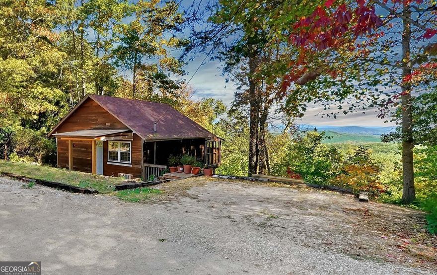 Enjoy stunning long-range mountain views from this charming cabin set on a quiet gravel road that's easily accessible from Hwy 136-no steep roads to climb and a completely level driveway with parking for two cars! Located half-way between Dawsonville and Jasper and set almost a mile from Hwy 136, the only sounds you'll hear here are the eagles and the breeze coming through your screened porch. At 1499 Eagle Ridge Road, you'll wake up every morning to panoramic mountain views right from your bedroom, which you can also enjoy from your back deck, the kitchen, the living room, the second bedroom, and your other back deck! With a completely open floor plan and windows along the length of the home, this would make the perfect full-time home with plenty of room for entertaining, a weekend getaway, or an Airbnb. The main floor features vaulted ceilings, wood floors, a brick fireplace, and oversized sliding glass doors opening to one two 24' wide covered decks. The lower level offers two bedrooms (one with a second brick fireplace), a full bath, an additional bonus room perfect for an office or studio, as well as a second 24' wide covered deck! Rare opportunity to get a panoramic mountain view at this price point. Backs up to thousands of acres of DNR property providing longterm privacy! Home needs some TLC and renovations.