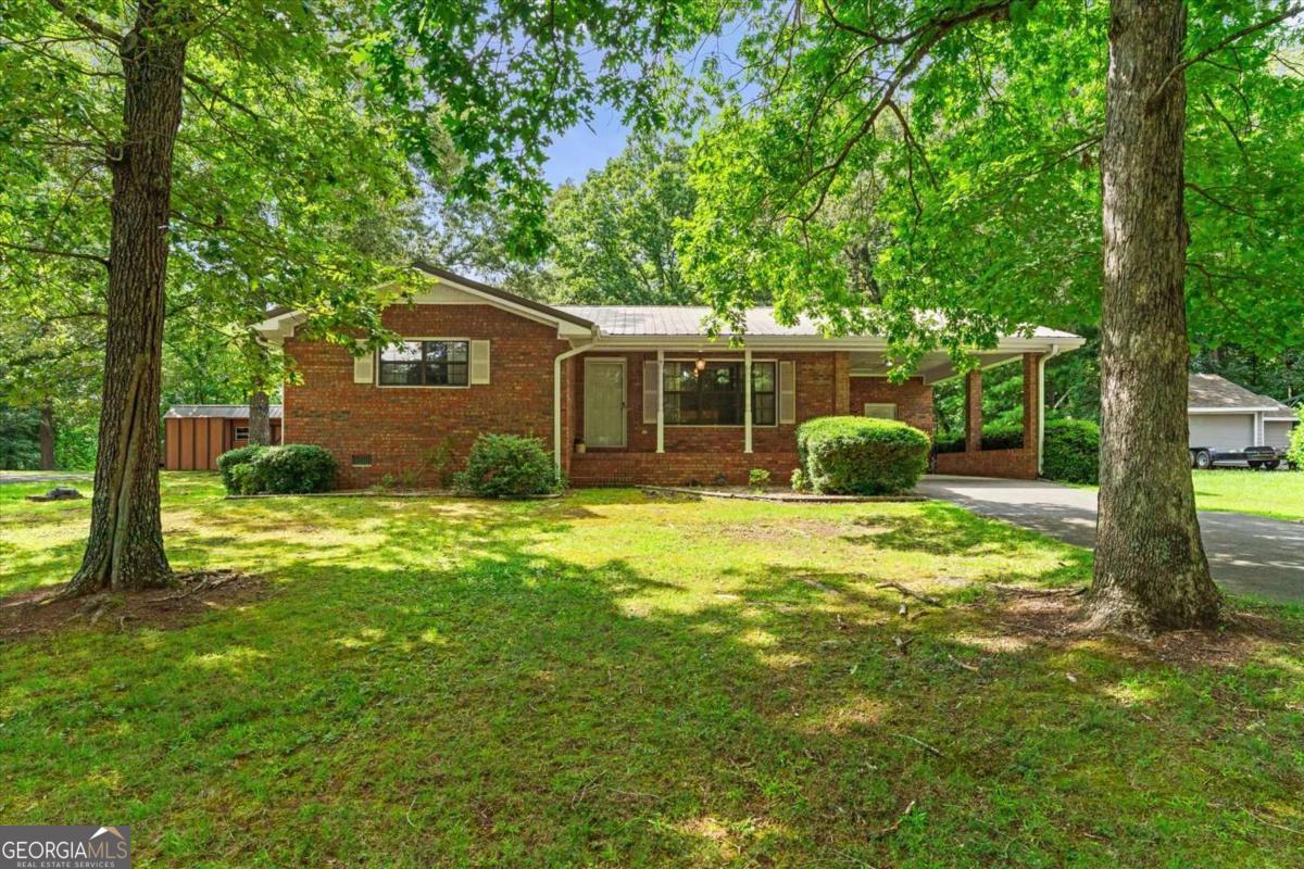 Located just minutes from downtown but tucked into the quiet charm of Chatsworth, this all-brick 2-bedroom, 2-bathroom home offers comfort, function, and a peaceful setting near the beauty of Fort Mountain. Enjoy the welcoming front porch, level yard with mature trees, and concrete driveway leading to a 1-car attached carport with a separate storage room. Inside, the layout includes a spacious living room, a dining area just off the kitchen, and a kitchen with generous cabinet and counter space. The laundry room features built-in cabinetry and an exterior door for added convenience. The primary bedroom suite offers two walk-in closets and a private full bath. The second bedroom includes a double-door closet and is near the hall bath with extended vanity. Situated in a small mountain town setting, this property combines low-maintenance living with access to local parks, schools, and outdoor recreation.