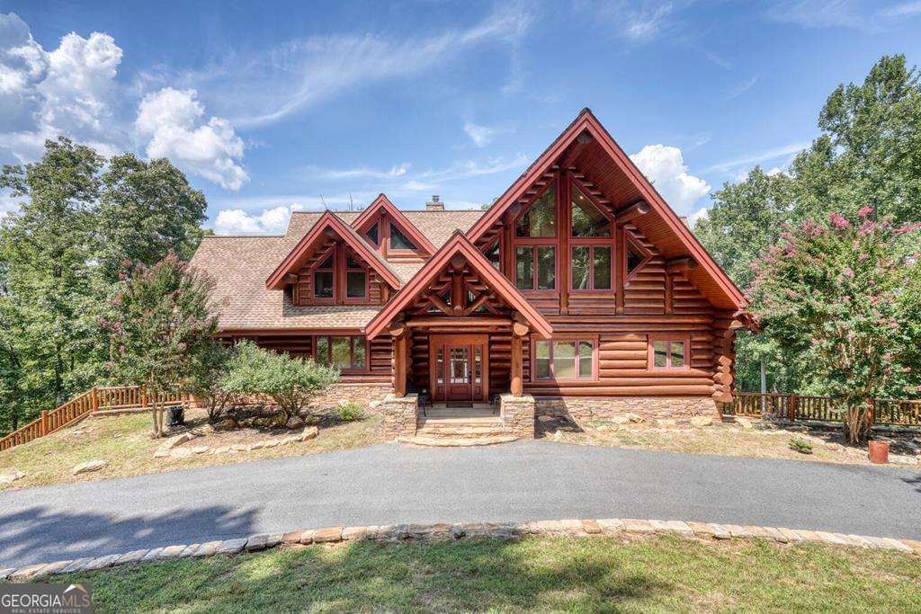 Perched high above Lake Nottely with sweeping mountain views, this custom-built lodge-style log home showcases the warmth of massive Douglas Fir timbers imported from British Columbia. Meticulous craftsmanship shines throughout with soaring ceilings in the great room and primary suite, complemented by 10' ceilings across the main level. The open floor plan flows effortlessly to expansive decks and patios, creating an entertainer's dream with endless views. The chef's kitchen boasts Thermador appliances and a built-in Sub-Zero refrigerator. The main level hosts a luxurious primary suite, an additional en-suite bedroom, and a convenient half bath. Upstairs offers a spacious loft and another en-suite, while the terrace level provides a cozy den with fireplace, wet bar, a guest suite, plus both a full and half bath. Two oversized 2-car garages, a workshop, and an elevator add unmatched convenience. Set on over 4 wooded acres with paved access, this private retreat combines rustic elegance with modern luxury. Being sold mostly furnished.