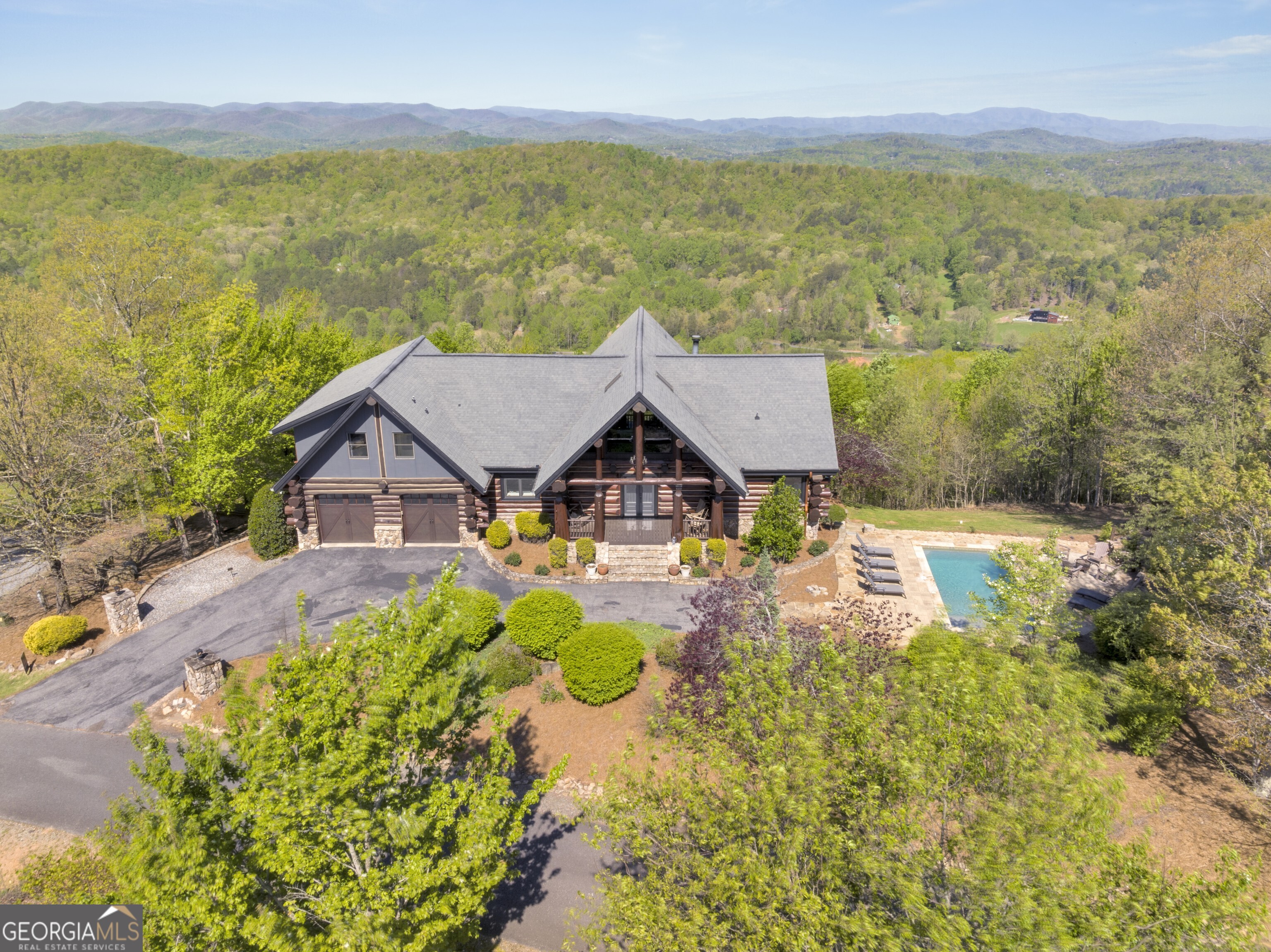 Welcome to this grand mountaintop Canadian Log home in the heart of the Aska Adventure Area with the best views in Blue Ridge! Available fully furnished for your immediate enjoyment. This spacious home has 5 bedrooms plus a bonus bunk room and loft, 4 full bathrooms, 2 half bathrooms, 2 kitchens, and rare 2 car garage. It recently underwent a complete remodel, including new kitchen, bathrooms, flooring, RH lighting, interior painting, exterior staining, and custom furnishings throughout. A new heated saltwater pool and separate hot tub provide endless relaxation and entertainment. Take in the breathtaking sunsets and long-range views from the expansive deck complete with gas fireplace, or relax inside and take in the row after row of beautiful mountains that greet you from almost every room. This private retreat is in the heart of it all in the Aska Adventure Area and Toccoa River, and a short 10-minute drive on all paved roads to downtown and Lake Blue Ridge. Currently a sought-after vacation rental with over $260,000 in annual revenue, or perfectly suited as a private residence, making this such a desirable property in Blue Ridge.