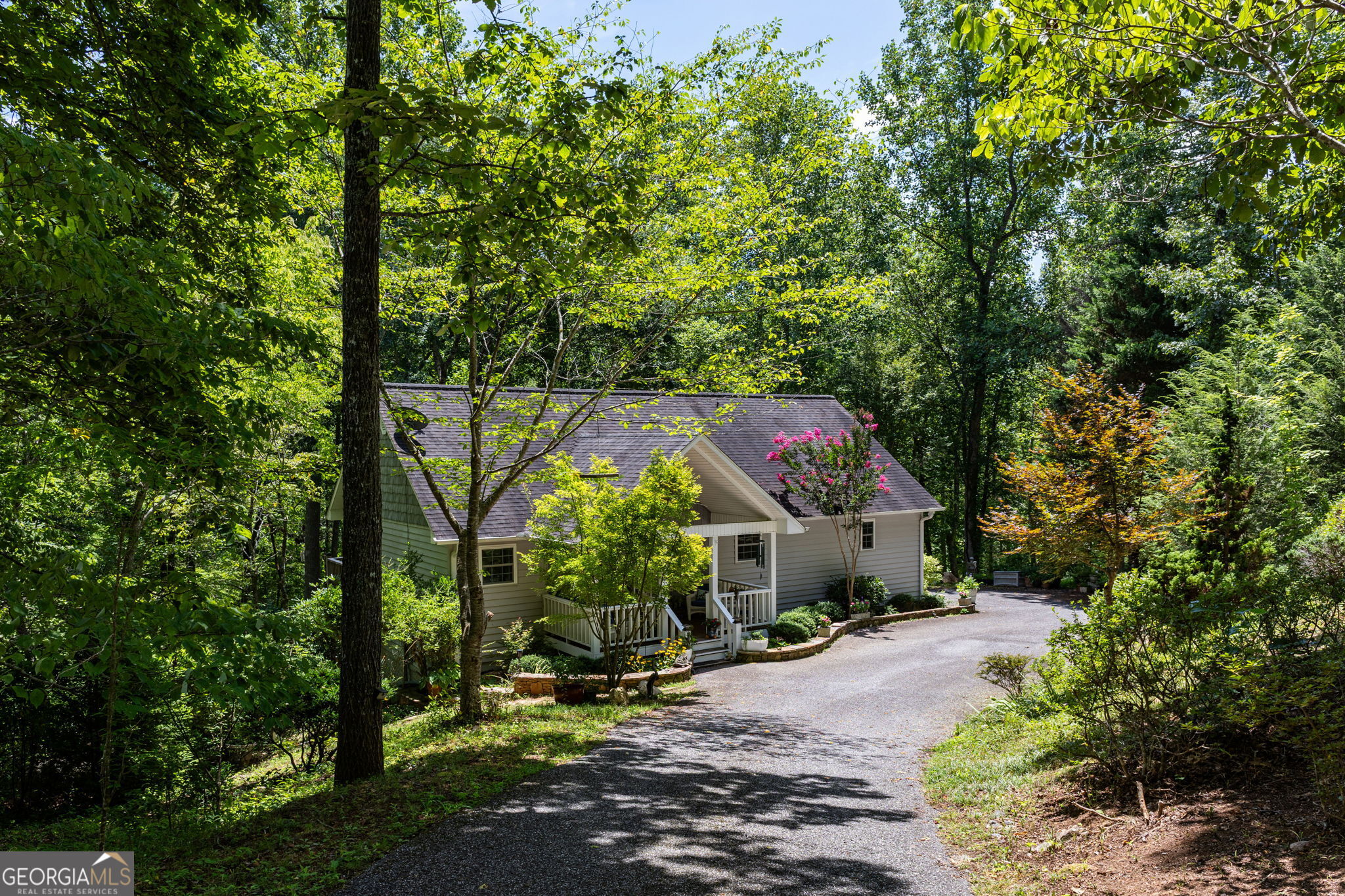 Charming creekside cottage in the heart of Hiawassee, tucked near the end of a quiet cul-de-sac with seasonal views of Bell Mountain and the relaxing sound of Bell Creek just beyond the backyard. From the moment you arrive, you'll feel at ease surrounded by nature, an English garden blooming year-round, and the peaceful setting of the North Georgia mountains. Tube or wade right into the creek from your backyard, or enjoy the community picnic area along Bell Creek, perfect for gathering with friends and neighbors. Inside, the home balances warmth and function with hickory wood and ceramic tile floors, double-pane windows, and an inviting gas fireplace in the living room. The updated kitchen includes granite countertops, custom cabinets, soft-close drawers, a movable island, and stainless steel appliances. A mud room sits conveniently by the entry. The main-level primary suite offers a spa-like bath with a soaking jet tub and a huge walk-in closet. Bathrooms are updated with granite counters, and the laundry room is located on the main level for convenience. The finished terrace level adds flexibility with soaring 10+ foot ceilings, a massive stone fireplace, a full kitchen, washer/dryer hookups, and a private entrance-making it ideal for an in-law suite, guest quarters, or rental potential. New carpet has been added to the stairs, and the home provides abundant storage throughout. Additional features include high-speed fiber internet for seamless work or streaming, and furnishings negotiable with sale. This one-owner home has been impeccably maintained since construction and is truly move-in ready. Located just minutes from Lake Chatuge for boating and fishing, Jack Rabbit State Park for hiking and biking, and year-round concerts and festivals at the Georgia Mountain Fairgrounds. This property offers not only a beautiful home, but also a lifestyle surrounded by the best of North Georgia recreation, culture, and natural beauty.