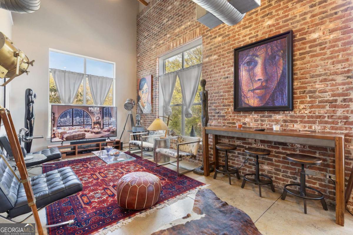 Discover vibrant luxury in this furnished industrial loft near Marietta Square. This 2-bedroom, 2.5-bathroom space combines nostalgic charm with modern urban style, ideal for those who appreciate the finer things. Crafted by a classic film enthusiast, the loft features an open concept living area with industrial chic furnishings, exposed brick walls, high ceilings, and large windows that fill the space with natural light. The gourmet kitchen boasts stainless steel appliances and sleek countertops, perfect for culinary adventures. Bedrooms offer peaceful retreats with vintage movie memorabilia. The main bedroom includes a spacious lounge area and ample storage. Located near Marietta Square, enjoy easy access to dining, shopping, and entertainment. This loft's cinematic charm and prime location make it a must-see. Schedule a private showing today!