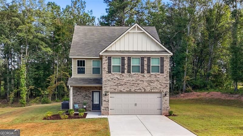 Search no more! Looking for more space, privacy, and value than the average new construction? This move in ready 5-bedroom, 3-bath home located in the highly sought-after Ola High School cluster offers just that! Built in 2022 and set on a level 0.87 acre lot with wooded privacy, this brick front property offers a rare opportunity to enjoy newer construction at a price below the current new builds in the community. This freshly painted home boasts a smart, open-concept layout ideal for both everyday living and entertaining. High ceilings on the main floor enhance the spacious feel, while the living and dining combo centers around a modern fireplace and flows seamlessly into the island kitchen. Here, you'll find stainless steel appliances, a walk-in pantry, and plenty of space for cooking, gathering, and hosting. Natural light pours into every corner, creating a warm and welcoming atmosphere throughout. The main level includes a private bedroom and full bath, perfect for guests or multi-generational living, as well as convenient access to the two-car garage and a long driveway that adds additional parking capacity. Upstairs, vaulted ceilings elevate all four bedrooms. The oversized owner's suite will be your ultimate place of retreat and relaxation with features such a large walk-in closet, linen closet, double vanity, and separate soaking tub and shower. Space for everyone in the family is never a question with three additional bedrooms offering generous layouts and ample closet space. The well-appointed split full bath offers flexibility, storage and comfort for everyone. The ample upstairs laundry room keeps everyday routines efficient and easy. Outdoor living is just as comfortable, with a covered front porch perfect for relaxing and a rear patio overlooking the wooded portion of the lot that adds both privacy and peaceful views. The home is wired as a smart home and located in a serene HOA community where common area maintenance is included. If you're looking for more space, more privacy, and more value than the average new build, this one checks all the boxes. Schedule your showing today and experience the difference for yourself.