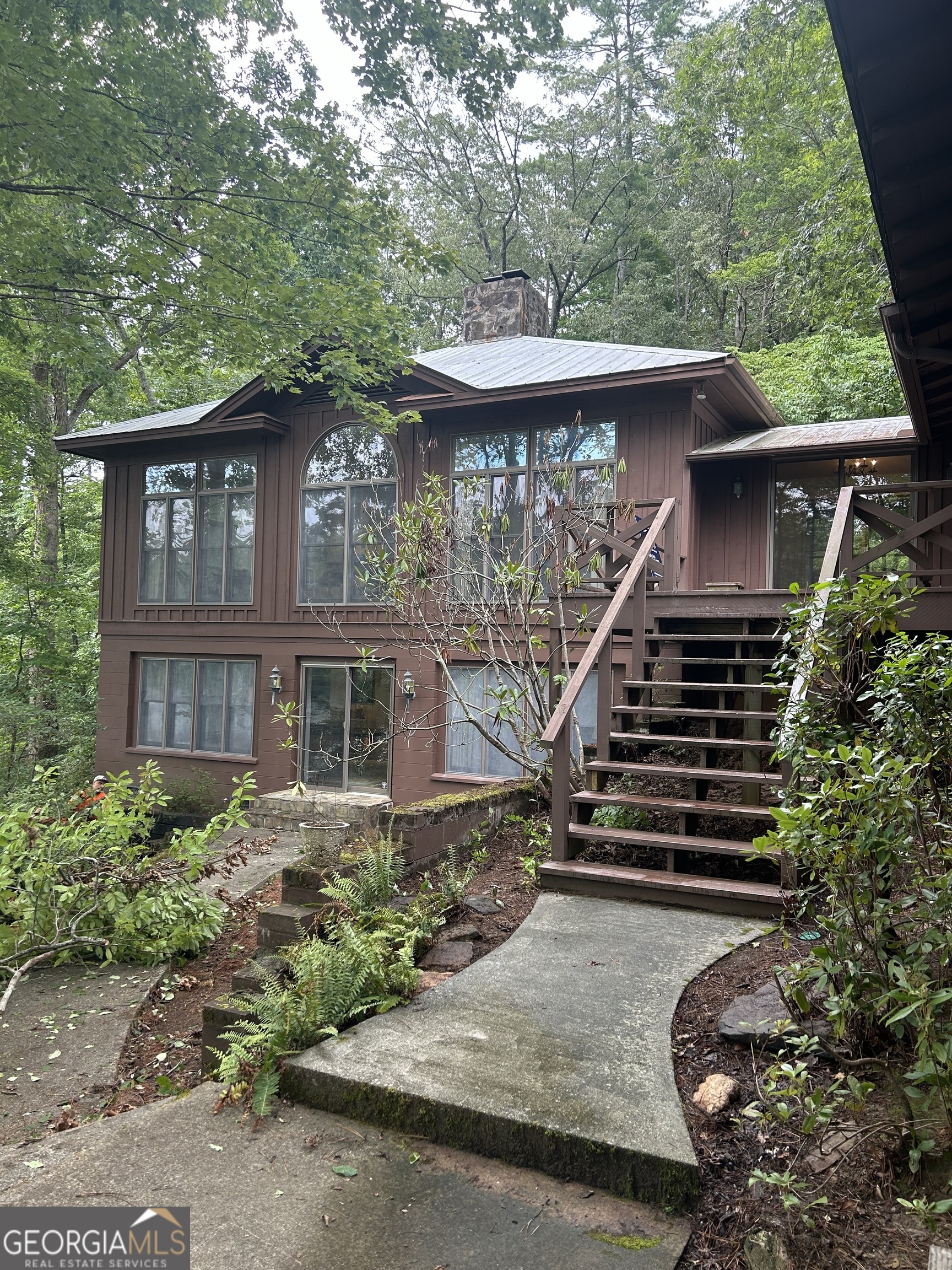Ideally situated on one of Lake Rabun's largest lots, is this historic lakefront house with big water views and a gradual slope to waters edge. The 5.5+/- wooded acres nestles a unique retreat with unusual privacy on this exceptional point on beautiful Lake Rabun. The charming 1930's cabin with 3 bedrooms, stone fireplace and screened porch has been connected to the 1990's 4 bedroom, 3 bath house. A country kitchen and dining area unite the old with the new. With water views from all sides of the house and privacy, this location on a point provides outstanding advantages. The main level of the modern side of the house boasts an inviting, light filled Living room with fireplace, a primary suite with bath, and a large guest suite with bath. The bright terrace level hosts a large entertaining room with fireplace and two guest rooms with shared bath. A patio off this room expands the entertaining area and offers access to the pathways that lead to the two boathouses and two sandy beaches on either side of the point. The two story, two stall boathouse was constructed to accommodate more modern watercraft while the one story boathouse is home to the antique wooden boat and fishing boat. Enjoy swimming in the two coves that flank this special point or use the sandy beaches on each side. A stone lake wall protects approximately 600 ft of shoreline. The property has a septic permit from the Rabun County Health Dept. for 7 bedrooms which is a rarity on the lake. Make this your second home or primary residence; remodel, renovate or build your dream home on this extraordinary property. Just 20 minutes to Clayton, 10 minutes to Lakemont Village, take the boat to Hall's Boathouse and the Lake Rabun Hotel in just 5 minutes. Convenient access with paved roads and paved driveway to the doorstep. This is a GA Power lease lot and requires a transfer fee.