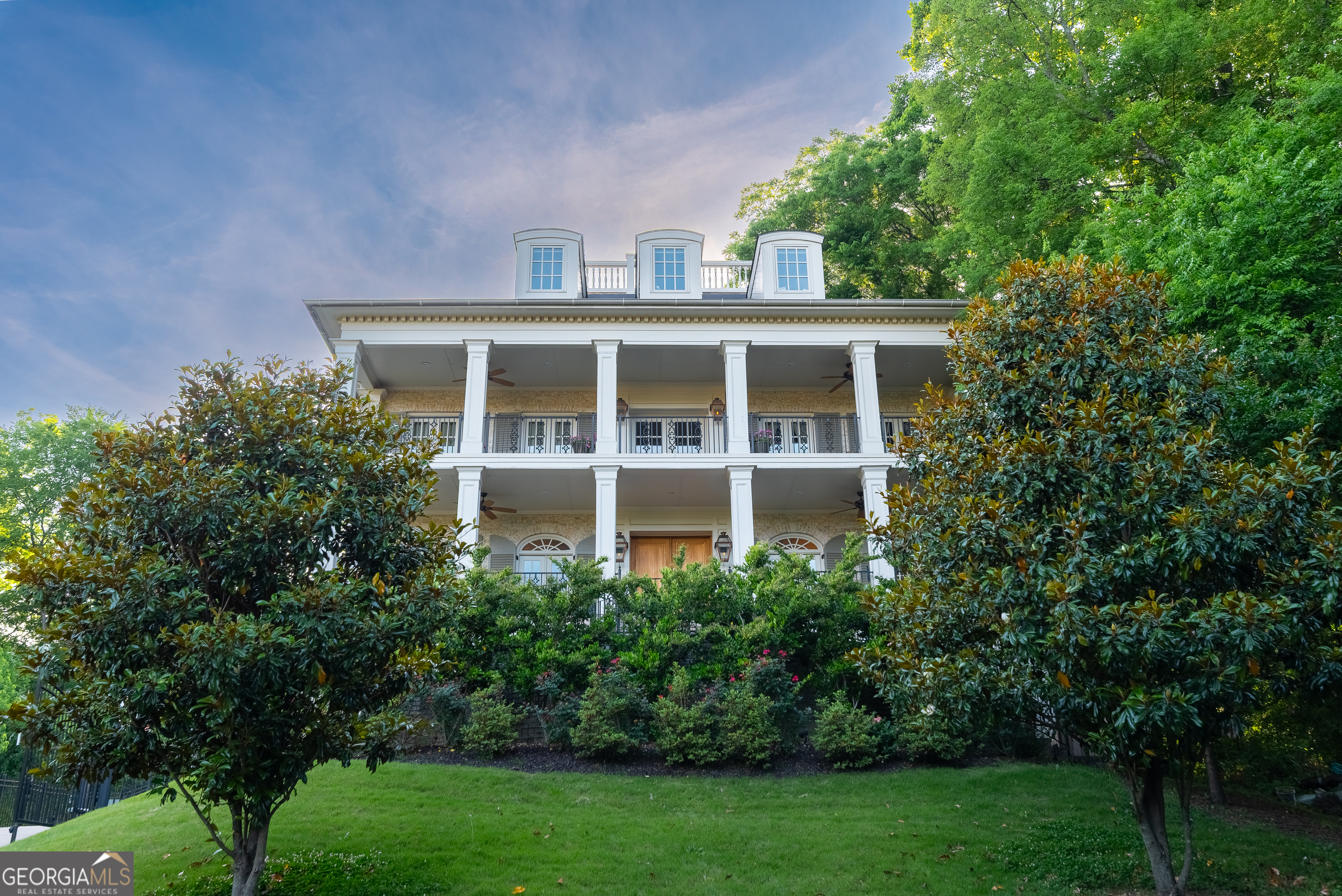 Welcome to an icon of Midtown, where modern-antebellum elegance and resort-style amenities meet on the largest residential lot in the Midtown Garden District. Tucked quietly away from the street, yet instantly recognizable from the BeltLine, this residence commands attention with its double-height verandas, elevated site, and a one-of-a-kind widows walk offering sweeping 360 skyline views and sunsets you wont forget. Completed in 2017 and thoughtfully expanded since, the home unfolds across 6,898 finished square feet on four levels, delivering eight bedrooms and seven and a half baths. The classic facade is lined with eight sets of French doors, flooding the main floor with light and opening directly onto the verandas. Ten-foot ceilings crown the main level, which also boasts its own laundry for added convenience. Step outside to a heated salt-water pool, perfectly positioned for privacy and effortless entertaining, with two additional sets of French doors leading to the backyard oasis. The vaulted owners retreat is a world unto itself. Enjoy serene pool views, direct access to the veranda, a separate sitting room with a mini wet bar, and a private connection to an adjoining bedroom ideal for a nursery or home office. On the third floor, another laundry room complete with a sink and generous folding space makes everyday living seamless. The fourth level offers two spacious bedrooms, abundant attic storage, a Jack-and-Jill bath, and access to the rooftop deck, where the city unfolds in every direction. Downstairs, host guests in a private suite, stay active in the professional gym, unwind in the steam shower, and rest easy with a concrete-encased panic room. The three-car garage is EV-ready for modern convenience. Estate-scale grounds blend with Midtowns walkability: stroll three minutes to the Eastside BeltLine Trail, Home Depot, Whole Foods, Trader Joes, and Ponce City Market; Piedmont Park is just a ten-minute walk away. This is more than a home, it's Midtowns landmark estate, offering rare land, unforgettable views, and the kind of privacy and access that's only possible here.