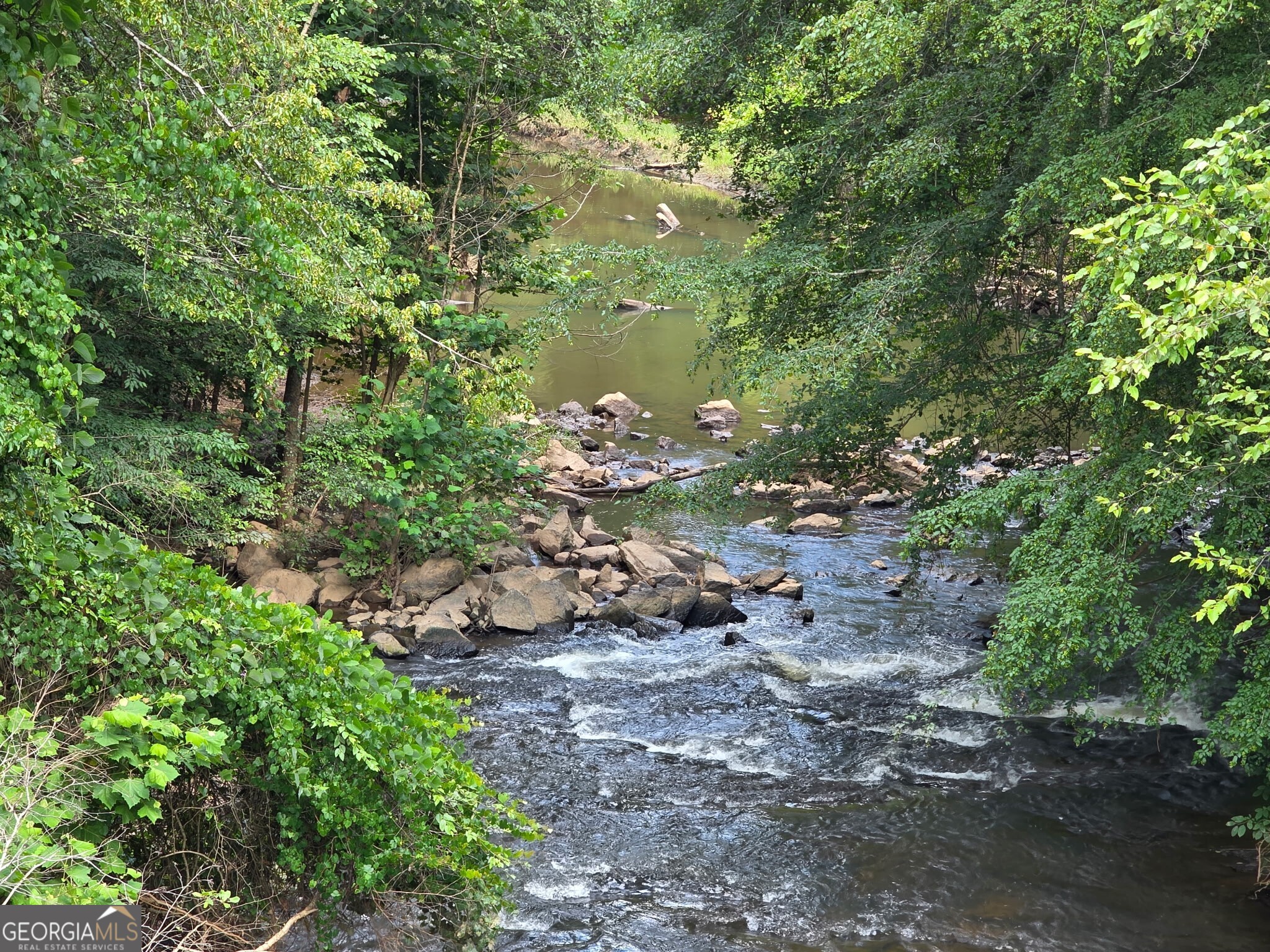 Discover the perfect blend of privacy, adventure, and natural beauty on this stunning 5-acre lot nestled along Bear Creek. Just minutes from local shopping yet worlds away in peaceful seclusion. Bear Creek flows directly into the Chattahoochee River, giving you rare water access right from your own property. Launch an airboat or raft for an afternoon escape, or simply relax and take in the sounds of nature. Depending on your future home's elevation, you could enjoy breathtaking views of the river from your own porch. This unique property is not in a flood plain, making it an ideal spot to build your dream home. Embrace rural living with all the modern conveniences close by. This is Georgia living at its finest.