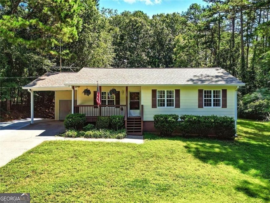 Set on a wooded lot with mature trees, this single-level home offers a smart layout designed for flexibility. A 2001 addition expanded the space to include a second primary suite with its own bath, a large family room, and a generous storage area.  The front porch welcomes you with room for seating, while the back deck overlooks a grassy yard bordered by trees for privacy. Inside, the kitchen features solid wood cabinetry, a center island, and a stainless steel side-by-side refrigerator. A gas range and adjacent pantry make meal prep practical, and the laundry room is just steps away for easy access.  Four bedrooms and three full baths mean everyone has their own space, while the living areas provide plenty of room for gathering. Recent updates include a new roof (March 2025), upgraded windows, encapsulated crawlspace, and a freshly serviced septic system (April 2025). An extra parking pad offers convenience for guests or additional vehicles.  Located near Interstate 575 & minutes from downtown Woodstock's shops and dining, this home balances privacy with accessibility. Price reflects the opportunity to make cosmetic updates to suit your style while enjoying a well-maintained, move-in-ready structure.