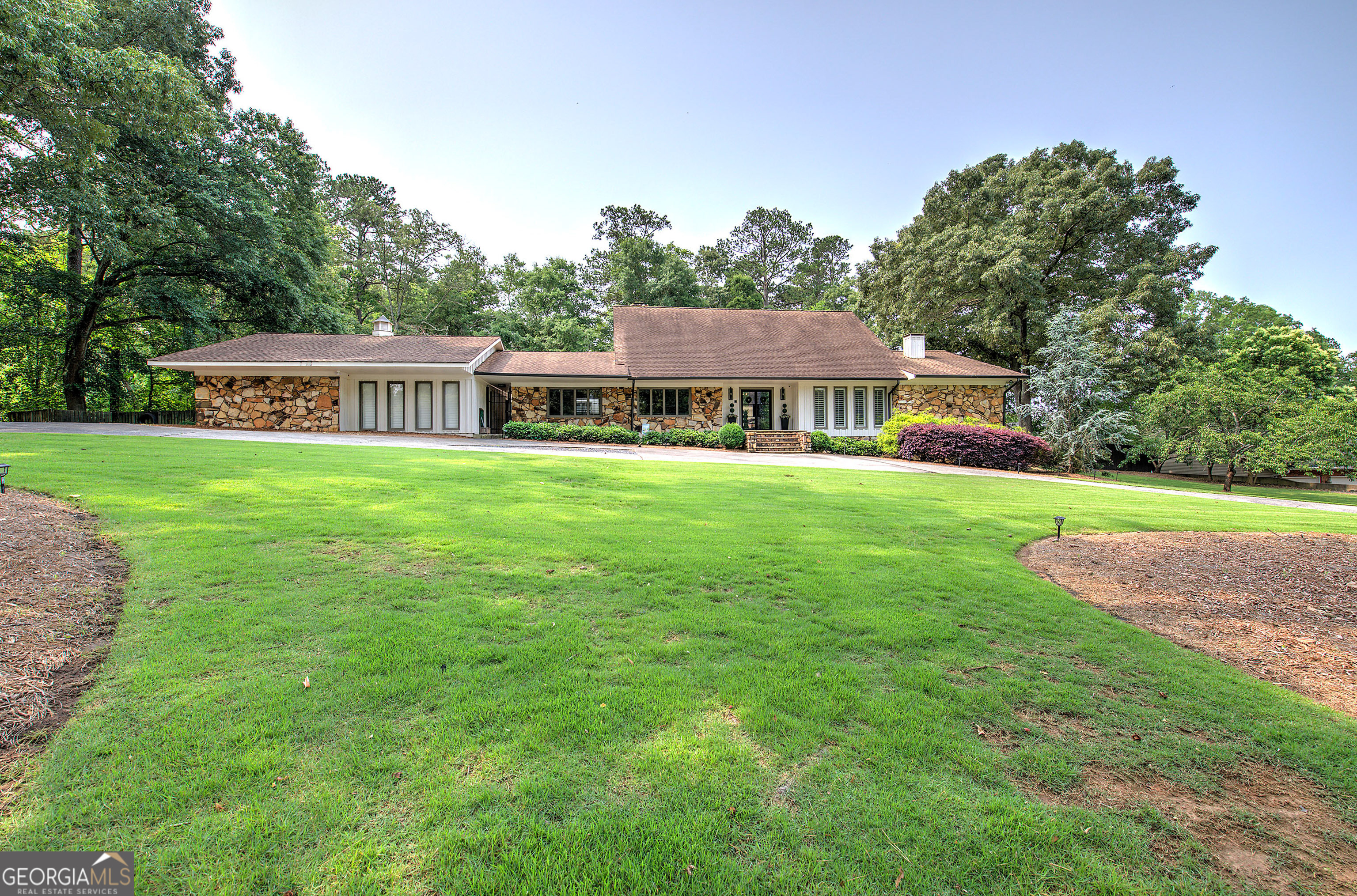 Welcome to a spectacular home on 1.6 acres in the most sought-after city of Cartersville. Amazing location in established neighborhood with a short walk to CES and Dellinger Park. A true entertainer's dream, this masterfully upgraded home offers refined Southern charm with exceptional outdoor living and thoughtfully curated interiors designed for luxury and comfort. From the moment you arrive, the inviting circle drive, rock front porch and custom metal and glass double front doors set the tone for what lies within. Rich hardwood floors lead you through a flowing layout that seamlessly blends classic architectural details with modern sophistication. The elegant foyer with its designer wallpaper and custom light fixture welcome your guests. A formal dining room exudes elegance with another stunning light fixture, wood beams and a wall of windows -perfect for hosting unforgettable gatherings. The heart of the home is the family room, anchored by a stunning stacked stone fireplace, dramatic floating staircase and bathed in natural light from the wall of windows overlooking your private resort-style oasis - the indoor heated pool with retractable roof. Perfect for year round entertaining or relaxation with your family. The chef's kitchen is a culinary masterpiece, featuring an oversized island, custom cabinetry, beverage bar with a wine cooler and custom wood shelving, built in double fridge/freezer, quartz countertops, a 6-burner KitchenAid gas range with double ovens and pot filler, a custom vent hood, a stylish tile backsplash and built-in desk. The open floor plan with the living, breakfast & kitchen can host even the biggest family. Retreat to the main-level owner's suite where luxury meets tranquility. This serene space includes beautiful hardwood floors and is large enough for a private sitting area with direct access to the pool & a separate private deck. The master bath is a spa-inspired en-suite featuring a grand tiled shower with dual heads, double vanities, soaking tub and a boutique-style walk-in closet with custom built-ins. Also on the main level, you'll find a private wing with it's own exterior entrance, a full guest bath for guests and plenty of storage. It also offers a large bedroom with its own full bath with custom cabinetry and a tile shower - all with a wall of windows and private access to the pool. Also on the main level an additional oversized den provides another space for entertainment with a custom metal & glass barn door, more wood beams and a pool table AND a huge home office with wood walls, its own half bath and a built-in bank safe AND an exquisite laundry room with floor-to-ceiling cabinetry, a beautiful sink and tile backsplash - can also be used as a butlers pantry for additional storage. The oversized 3-car garage has plenty of storage. Upstairs, discover two spacious bedrooms with walk-in closets, a full bath with more custom cabinets and generous storage space, including a walk-in attic. This rare gem is a showcase of custom design, timeless finishes, and impeccable craftsmanship. Don't miss your opportunity to own this unforgettable retreat.