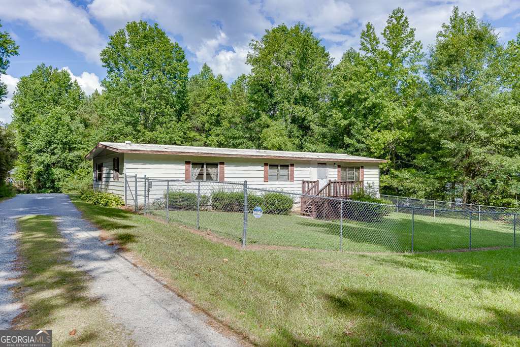 Own your own piece of privacy right in Buford! Just minutes from highway access and the Buford corn maze this usable piece of property can be your own slice of heaven. Located in Hall County, with traditionally lower property taxes this long rectangular property has approximately 91 ft of road frontage at it's widest in the back is 140 ft. (buyer to verify.) Utilities are located on the property. Sold with property is a 1972 double wide in great condition. All appliances stay with the home. Roof was recently replaced, some plumbing has been updated. Home is in good condition, you may choose to update. Home offers galley kitchen, large open living room with ample daylight and a LARGE screened in porch! The yard is also already fenced for your favorite fur babies. This property offers privacy and comfort close to shopping, restaurants etc. Whether you choose to live in the home or build your own this can be HOME. Property line goes roughly back to old cement lids for abandoned wells. Please do not bother back owner. Home does not qualify for FHA to VA, I'm sorry.