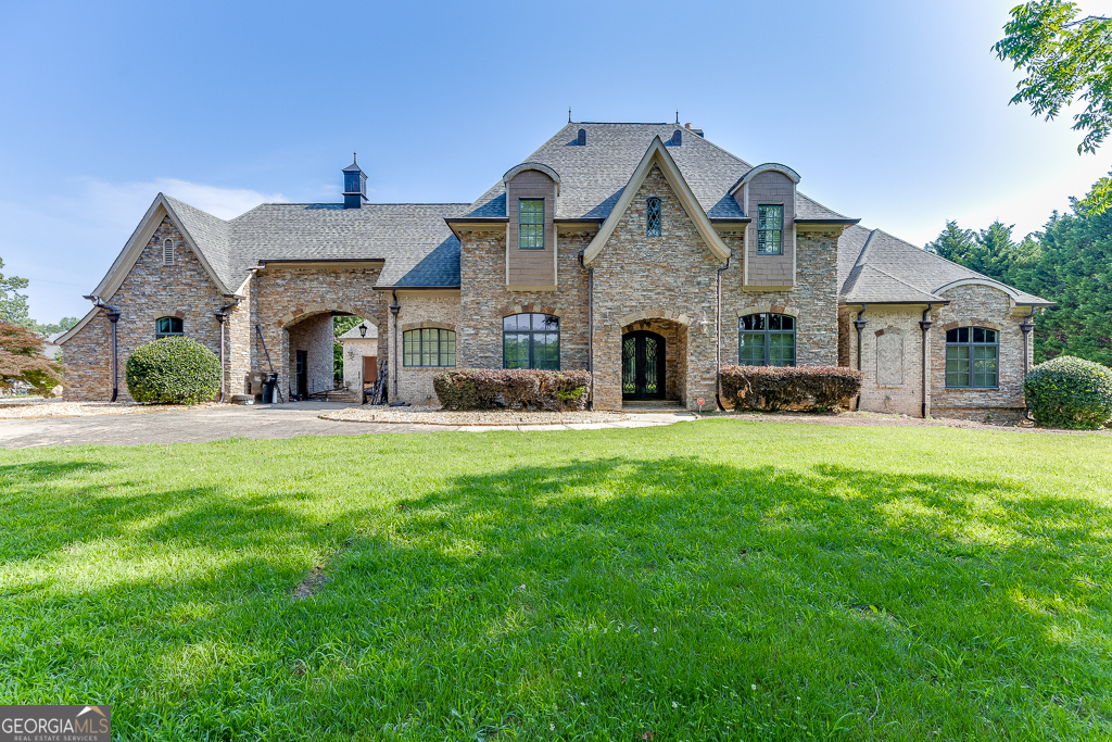Luxurious custom Buford estate spans over two acres with private gate, fully-fenced yard, stunning amenities, and expansive manicured grounds. Enjoy proximity to innovative Seckinger schools, convenience to shopping and dining, just minutes from adventures at Lake Lanier and Chateau Elan. The newly remodeled chef's kitchen features sub-zero refrigerator, spacious pantry, custom island and banquette, all opening to a welcoming family room and enclosed porch, overlooking a gorgeous saltwater pool with expansive stone decking. Primary Suite on main surveys the backyard oasis, featuring a grand fireplace, lovely en suite bath, and dual closets (including an expanded shoe closet). Upper level features a large bonus room, two additional bedrooms with shared bathroom, another large fireplace, family room, and additional storage. Terrace levels boasts a full kitchen, vast Media Room, Billiards Room, Poker Room, and ample storage space. The covered patio is an ideal spot to enjoy a day in the shade. Truly embrace four season living - poolside, in the spa, or by the fireplace. This exquisite residence includes six bedroom suites, three car garage, and a family room per floor. With plantation shutters, exceptional woodworking and built-ins throughout, it awaits your personal touch. Shown by appointment only - Listing Agent to provide access.