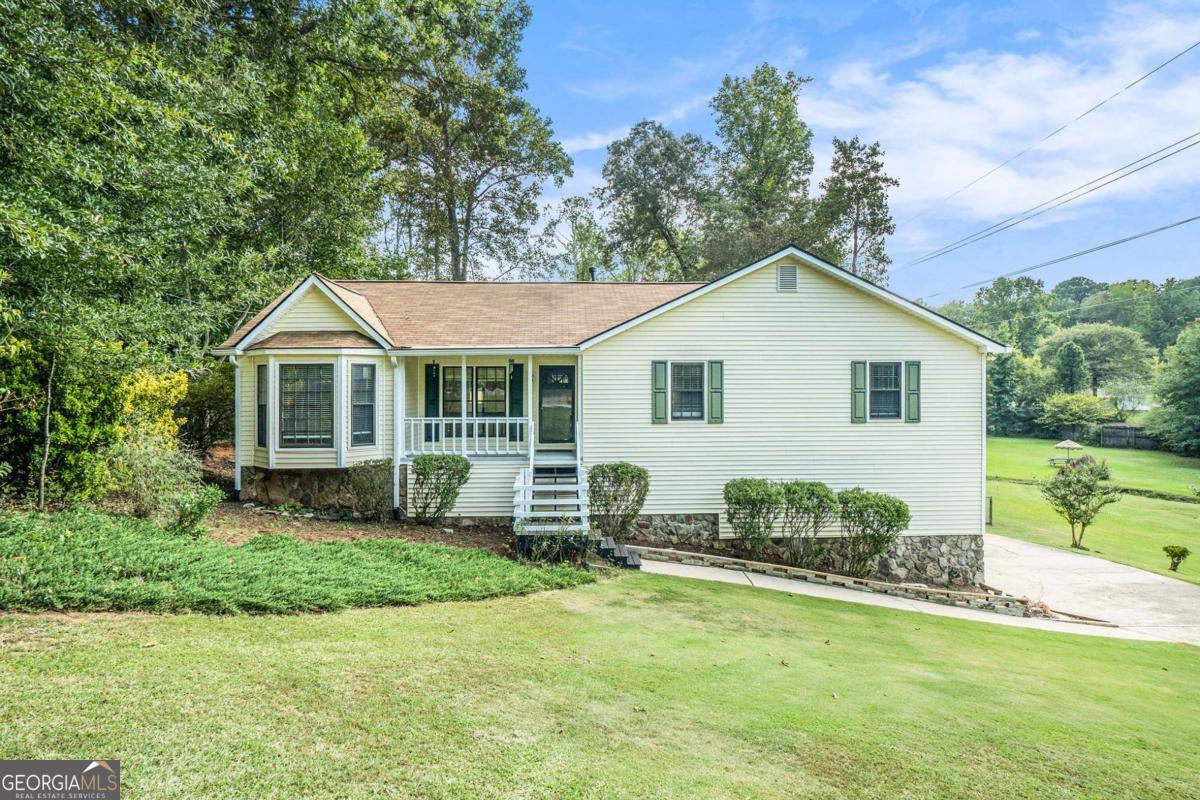 Conveniently located just minutes from I-575, this 3-bedroom, 2-bathroom home in Woodstock offers a spacious layout, updated features, and no HOA restrictions-giving you the freedom to truly make it your own. All bedrooms are on the main level, including a primary suite with a separate soaking tub and shower, a walk-in closet, and access to a private balcony overlooking the fenced backyard. The updated kitchen features a stainless steel farmhouse sink and a window view into the living room, which boasts vaulted ceilings and a stone-faced fireplace. A separate dining room adds extra versatility to the floor plan. At the back of the home, a sunroom provides a peaceful space filled with natural light. Downstairs, the basement includes a bonus room, washer & dryer connections, and access to the two-car garage located on the lower level. The covered wood deck off the basement offers another great space for outdoor living. Enjoy a quiet lifestyle with no HOA, while being close to shops, dining, and commuter routes. This home is a rare find in a great location! Discounted rate options and no lender fee future refinancing may be available for qualified buyers of this home.