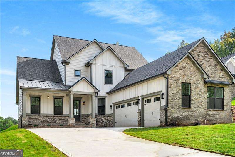 Welcome to life in the highly coveted Traditions of Braselton-a prestigious, resort-style community where elegance meets everyday convenience. This brand-new construction home is a masterful blend of modern sophistication and cozy charm, meticulously designed with top-tier finishes and an open-concept layout perfect for today's lifestyle. Situated on a prime walk-out basement lot, this home offers seamless indoor-outdoor living, leading to a vast, level backyard-ideal for entertaining, play, or simply unwinding in your private outdoor oasis. From the moment you arrive, the rocking-chair front porch and spacious three-car garage set the tone for the warmth and grandeur that await inside. A soaring foyer welcomes you, leading to a flexible space ideal for a home office, playroom, or formal sitting area. At the heart of the home, the chef's kitchen is a true showstopper-featuring shaker-style cabinetry, quartz countertops, stainless steel appliances, a wine fridge, coffee bar, and a large walk-in pantry. Whether you're hosting a dinner party or preparing a quiet meal, this kitchen is designed to impress. The two-story family room is centered around a cozy fireplace and seamlessly flows into the covered back porch, complete with an "outdoor living" fireplace-the perfect spot to relax and take in the seasonal views. This home offers a rare double master bedroom layout, perfect for multi-generational living or added flexibility. The main-level owner's suite is a private sanctuary, featuring a spa-like bath with a soaking tub, frameless glass shower, his & hers vanities, and a generous walk-in closet. Upstairs, a second owner's suite provides another spacious retreat, while two additional bedrooms, a second-story family room, and a media room offer ample space for rest, recreation, or entertaining. Living in Traditions of Braselton means enjoying a fitness center, junior Olympic pool, tennis & pickleball courts, and an on-site restaurant, all just minutes from Publix, shopping, and dining. Don't miss your chance to own this stunning new construction home in one of Georgia's most sought-after communities. Secure your place in Traditions of Braselton today!