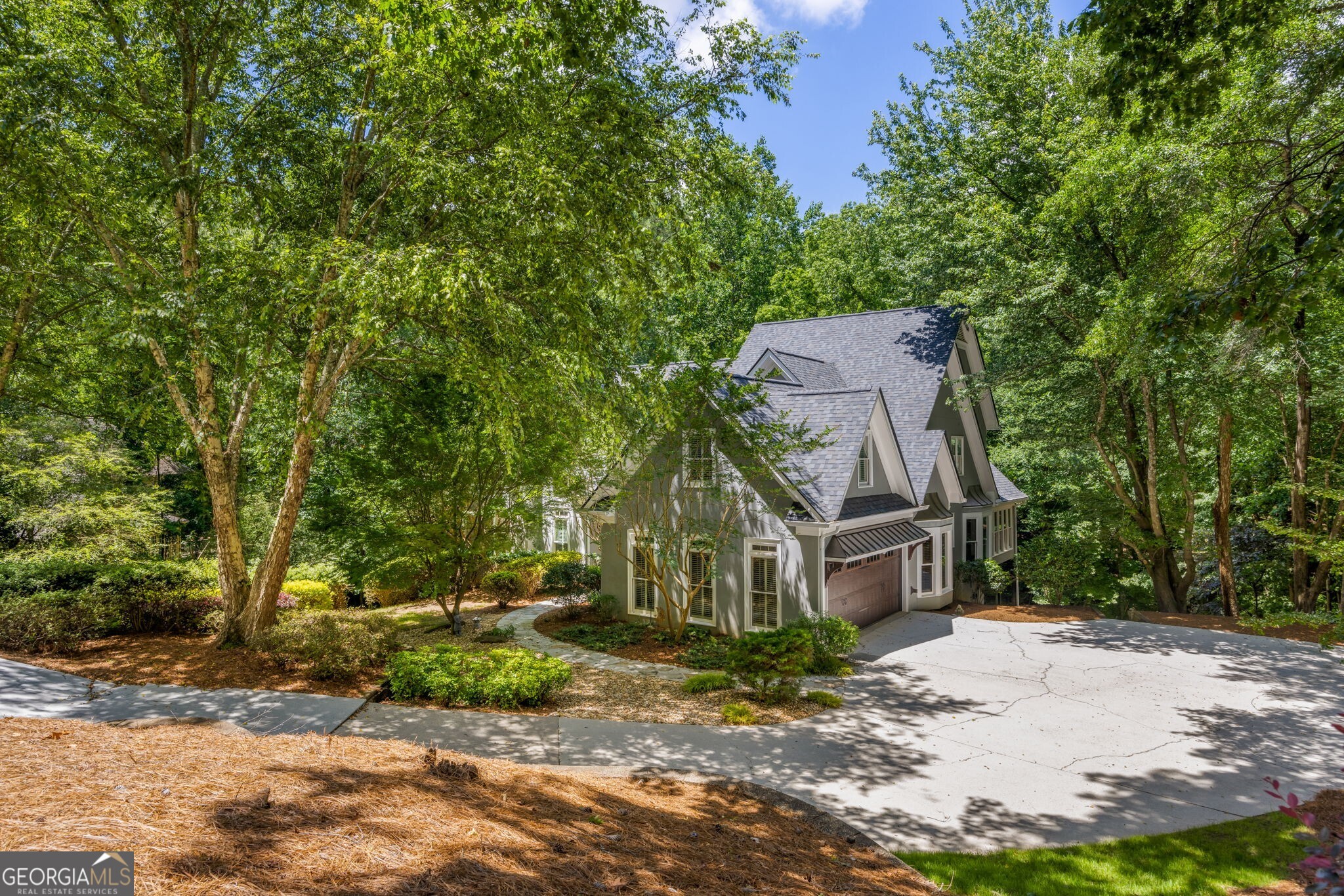 Welcome to 410 Waterridge Court, a beautifully appointed custom home tucked away on a private 1.1-acre lot in the prestigious Rivergate neighborhood of Sandy Springs. Surrounded by mature trees and lush landscaping, this five-bedroom, four-and-a-half-bath home offers a perfect blend of timeless architecture and modern luxury across three finished levels. The main level opens with a dramatic two-story foyer featuring archways and a sweeping staircase. A vaulted great room anchors the space with a fireplace, built-ins, and French doors that lead out to an expansive main deck overlooking serene woods. A formal dining room sits just off the living area, ideal for entertaining with direct deck access. The chef's kitchen is outfitted with rich cherry cabinetry, granite countertops, a gas range, double ovens, a warming drawer, and a sunny breakfast nook. A vaulted sunroom with skylights and a stone feature wall adds a cozy, light-filled retreat just off the kitchen. The primary suite is conveniently located on the main floor and includes a fireplace, sitting area, and private access to the deck. Its spa-quality en suite bath is a true showpiece, featuring a frameless glass shower with river rock flooring and body jets, dual vanities, and stacked stone accents. A handsome executive office with wood paneling, built-ins, and bay windows completes the main level, along with a stylish powder room finished with a designer vessel sink and mosaic tilework. Upstairs, spacious secondary bedrooms offer generous closet space and access to updated bathrooms with custom tile and natural stone finishes. Downstairs, the fully finished terrace level is designed for both fun and function. The standout feature is a private home theater with elevated leather seating, a projector and screen, surround sound, and a cozy fireplace. An adjacent lounge area, game space with arcade cabinet, and wet bar setup offer the perfect setting for entertaining. A dedicated home gym with mirrored walls and rubber flooring provides a complete fitness solution. Options include full guest suite with private bath ensures comfort for visitors. Outdoor living is equally impressive, with multiple access points to the expansive main deck featuring built-in bench seating and a separate lounge zone. The lower-level patio offers a shaded retreat with space for additional seating or a future hot tub, while professionally landscaped garden paths lead to a wooded backyard offering total privacy and space to explore or relax. Additional features include hardwood and luxury vinyl plank flooring throughout, multiple fireplaces, new interior paint, new roof, pre inspected hardcoat stucco, an oversized two-car garage with built-in workshop space, ample storage, updated lighting, and a fresh, move-in-ready interior. Located just minutes from GA-400, top-rated public and private schools, and the Chattahoochee River parks and trails, this home offers the rare combination of luxury, privacy, and convenience in one of Sandy Springs' most coveted neighborhoods.