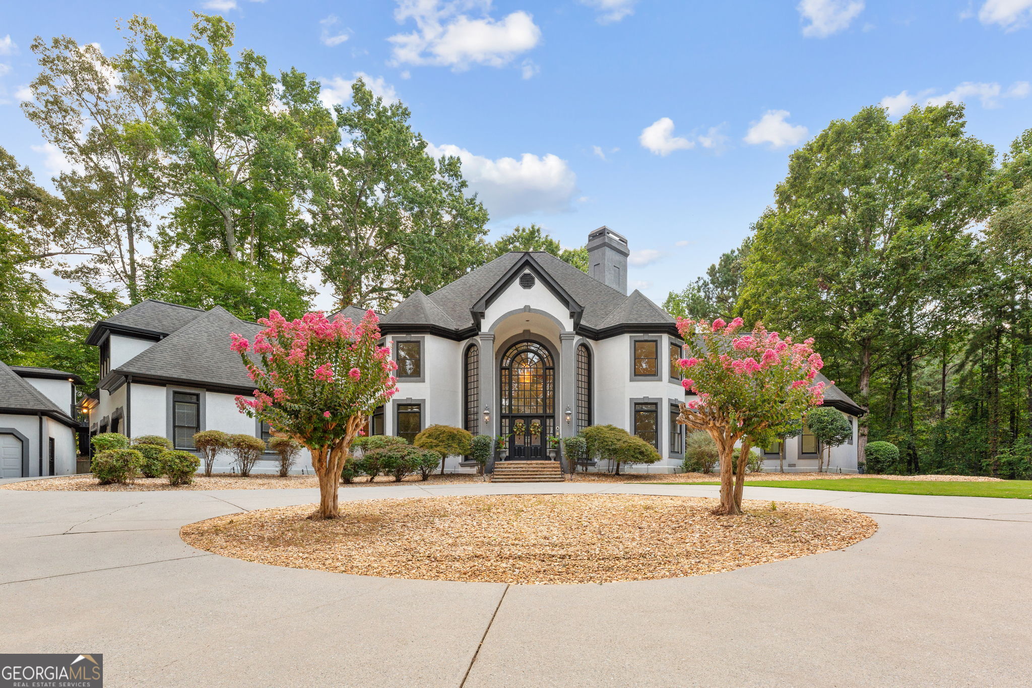 Welcome to Fairway Estates, one of the most prestigious gated enclaves in the heart of horse country. As you approach the stately entrance, you're greeted by twin fountains, towering brickwork, and ornate wrought-iron gates-a breathtaking prelude to the elegance that awaits within. Nestled on 3.99 manicured acres along a private lake, this estate captivates at first glance. A sweeping front lawn rolls down to the water's edge, setting a scene of serenity and grandeur. Beyond the gates, a magnificent carriage house with three-car garage and private studio apartment stands proudly, while the main residence offers an additional three garages-six in total-ideal for a discerning collector. The approach is nothing short of cinematic: flagstone steps ascend to soaring two-story arched windows, hinting at the grandeur within. Step inside, and you are welcomed by a spiraling staircase, gleaming marble floors, and a freshly refreshed interior designed for both intimate gatherings and large-scale entertaining. The formal living room, anchored by a fireplace and full bar, is framed in walls of glass, blurring the line between indoors and out. This space flows effortlessly into a sun-drenched sitting area and expansive kitchen, where sleek new quartz countertops and several prep areas make culinary pursuits a joy. A grand dining room and spacious laundry complete the main living areas. The primary suite is a sanctuary unto itself: an oversized bedroom, private office with spiral stair to an exercise room, dual walk-in closets with built-in safes, and a spa-inspired bathroom. Columns frame a luxurious soaking tub, while a dual-head shower and adjoining spa room with illuminated arched ceiling elevate the experience to resort quality. Upstairs, the residence transforms into an entertainer's paradise. Three ensuite bedrooms, a grand media room, and an impressive sunken pool room with mirrored shelving create endless opportunities for gathering and celebration. Guests enjoy the utmost privacy in the detached studio above the carriage house, while the backyard invites leisure with its resort-style pool, winding flagstone paths, and multiple terraces overlooking the tranquil lake. The potential buyer will be excited to bring their pool designer to make this portion of the property with their own style stamp. This is more than a home-it is a statement of refinement, a retreat of rare beauty, and an entertainer's dream, all within one of the region's most coveted addresses.