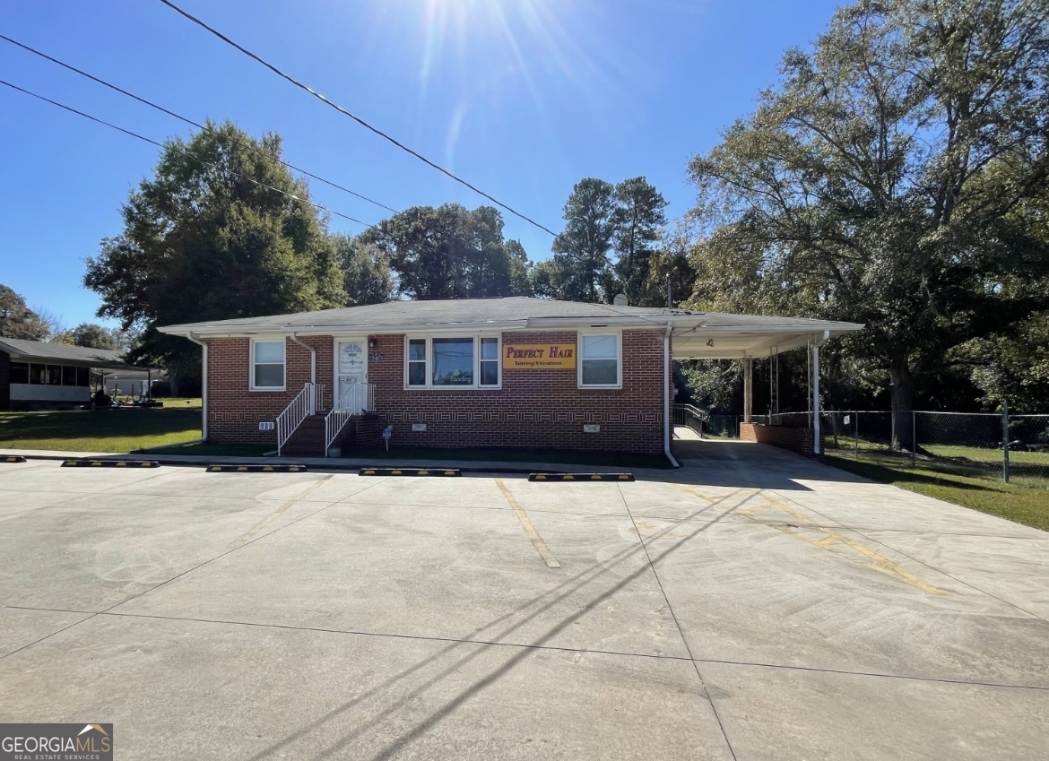 COMMERCIAL PROPERTY - PRIME LOCATION! All-brick building was previously a beauty salon, with endless possibilities for other uses! Features include, Lobby/reception area, Full kitchen and full bath, 4 additional rooms (ideal for offices, salon suites, or treatment rooms, Covered carport + 6 parking spaces (including handicap-accessible) Circular driveway with handicap ramp entrance, Large backyard + storage shed. Upgrades & Highlights are Beautiful hardwood floors, 4-sided brick with New vinyl windows, New Gutter/Leaf Guard system, New lighting, new roof, new circular driveway. HVAC only 2 years old. High traffic area with excellent road visibility, Easy access to Hwy 19/41, Close proximity to the airport and downtown Griffin. Perfect for a salon, medical office, professional services, retail business and more!