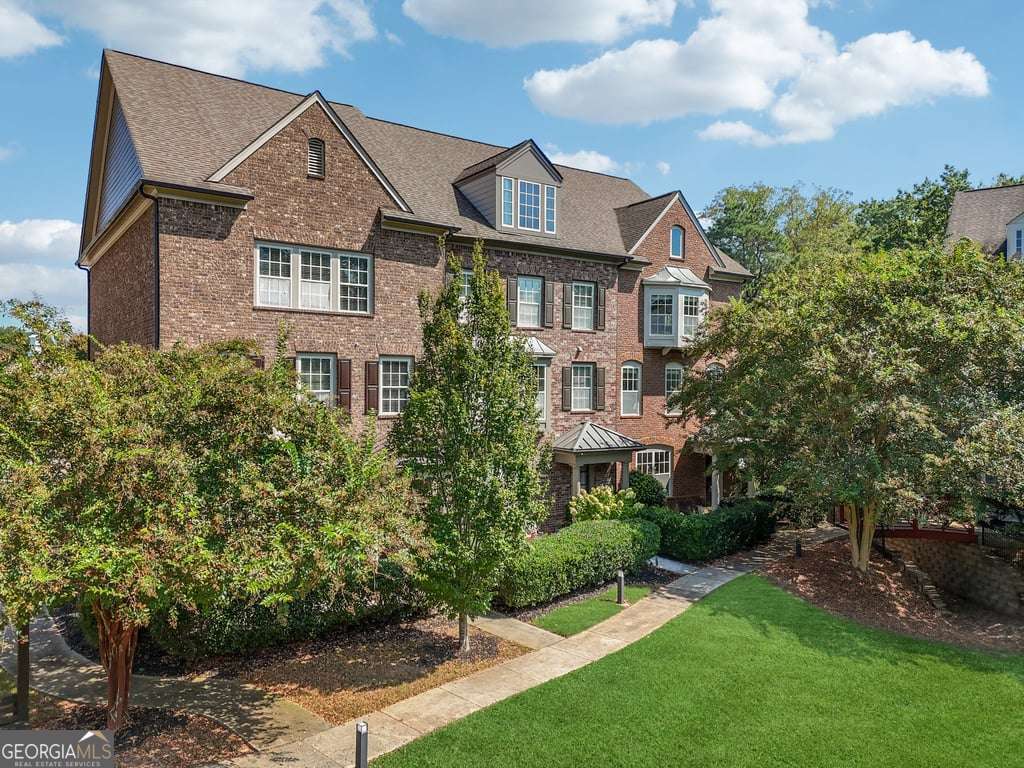 Tucked behind the beautifully manicured gates of Concord Hall, one of Smyrna's most cherished and impeccably maintained communities, this stunning end-unit townhome at 550 Micayne Circle offers a lifestyle as elevated as its John Wieland-inspired architecture. With timeless brick on all four sides and a prime corner position, this residence exudes charm from the moment you arrive, facing an enchanting courtyard that feels plucked from the pages of a fairytale. Step through the private front entry into a world where natural light dances across rich hardwood floors and crown molding, highlighting the craftsmanship and elegance that define this home. The main living space flows effortlessly with a modern open layout, anchored by a striking gas fireplace in the great room. Just beyond, the chef's kitchen awaits, appointed with granite countertops, custom cabinetry, a walk-in pantry, and a generous island that invites both culinary creativity and social gatherings. Adjacent, the separate dining room easily seats twelve or more, creating a perfect setting for intimate dinners or holiday feasts. Upstairs, the primary suite is a true sanctuary. A cozy bay window fills the room with morning light, while the spa-inspired ensuite offers dual vanities, a soaking tub, and a spacious walk-in closet. Two additional bedrooms, including a flexible terrace-level suite with full bath and private entry, offer space for guests, a home office, or even a fourth bedroom. Enjoy your morning coffee or an evening glass of wine on the front porch overlooking the lushly landscaped courtyard, or step out to explore the vibrant lifestyle that makes Concord Hall so desirable. Less than 10 minutes away, the Atlanta Battery and Truist Park serve as hubs of entertainment, dining, and nightlife, perfect for Braves fans and city explorers alike. The Silver Comet Trail invites morning jogs or weekend bike rides through scenic Georgia woodlands, while the beloved Smyrna Market Village provides an irresistible array of boutiques, eateries, and community events year-round. This townhome isn't just about elegant living, it's about connection. The Concord Hall community is tight-knit and prideful, with neighbors who care and a setting that's as serene as it is sociable. Tree-lined streets, charming green spaces, and easy access to I-285 and I-75 make commuting a breeze while preserving the peaceful ambiance of suburban life. Crafted with the timeless quality and thoughtful details expected from a John Wieland home, and lovingly maintained as a true gem of the neighborhood, this is more than a residence, it's a lifestyle statement. Welcome home to Concord Hall, where luxury meets location and community becomes family.