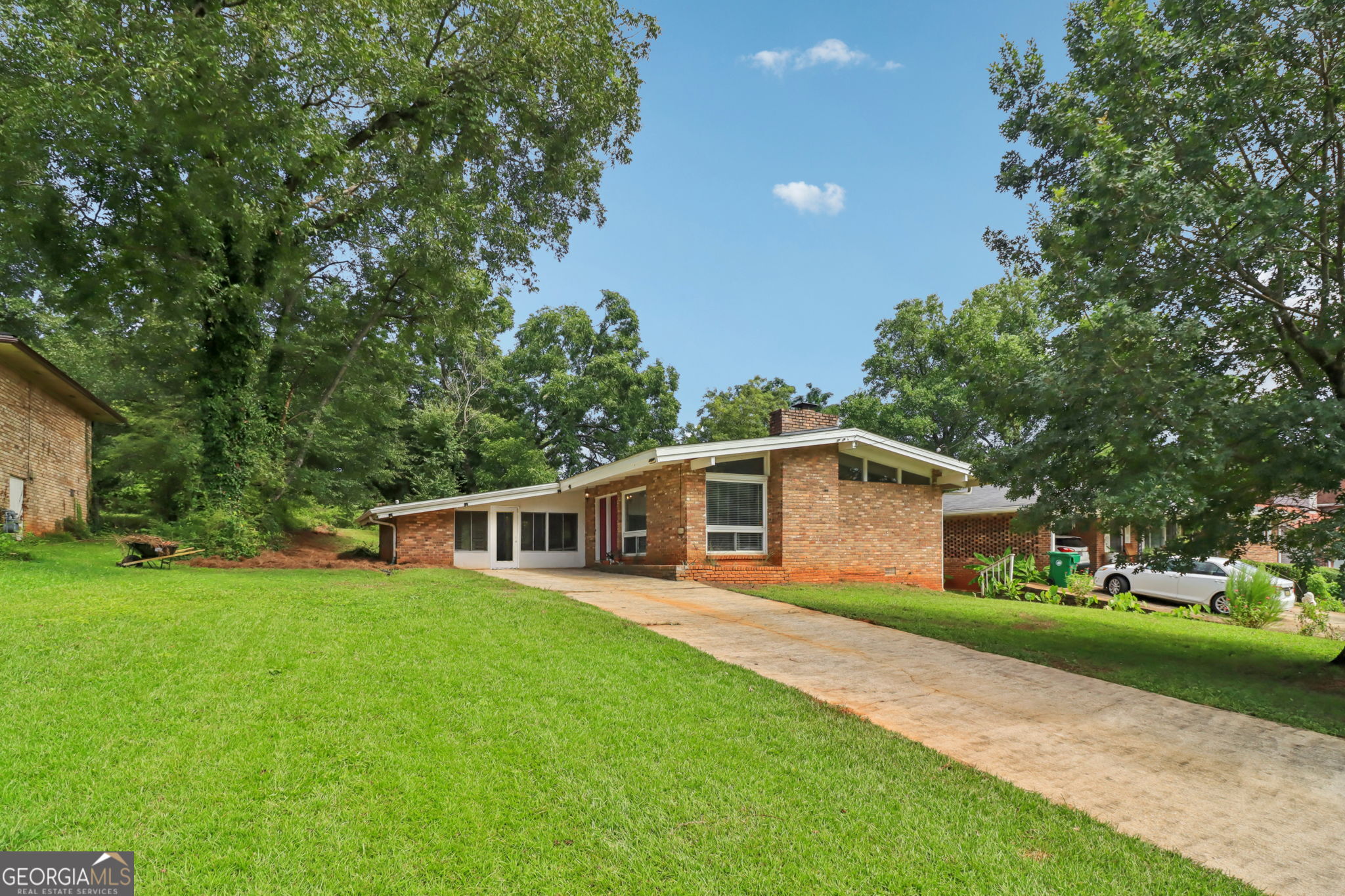 Midcentury character meets modern comfort at 2428 Parkland Drive. This 3-bedroom, 2-bath home with bonus room is a striking example of Frank Lloyd Wright-inspired architecture, with vaulted ceilings, exposed beams, and walls of windows that flood the interior with natural light. Original hardwoods and preserved vintage tile blend seamlessly with thoughtful updates, creating a home that honors its history while feeling fresh and contemporary. The large bonus room adds flexibility for a home office, gym, or media space. Outside, the private backyard is designed for entertaining with a custom patio and garden retreat, perfect for gatherings or quiet mornings. Located in a peaceful residential pocket, the home offers quick access to Decatur, East Atlanta, and Grant Park. N.H. Scott Park is right down the street with tennis and basketball courts, green space, and a new pool underway. For buyers seeking style, space, and convenience, this home delivers. Bold architecture, modern updates, and a prime intown location make 2428 Parkland Drive a rare opportunity.
