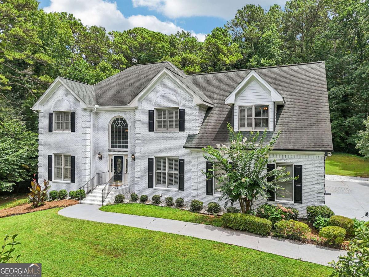 Welcome to this spacious and versatile home offering privacy, flexible living spaces, and no HOA. Tucked away at the end of a long private driveway, this peaceful retreat is surrounded by trees, providing a serene, wooded setting. This four-sided brick exterior gives the home timeless curb appeal, and the freshly painted interior provides a clean, move-in-ready feel. Inside, a two-story foyer opens to a large formal living room and a separate formal dining room ideal for gatherings. The main level features hardwood floors, tall ceilings, and expansive windows that fill the home with natural light. The living room centers around a fireplace and opens to the kitchen and breakfast nook. The open concept kitchen includes granite countertops and plenty of cabinet storage, while a large sunroom with hardwood floors and surrounding windows offers a bright and comfortable space for casual dining or relaxation. A door from the sunroom leads directly to the back deck, creating a seamless indoor-outdoor flow. The main level includes a bedroom and a nearby full bathroom, perfect for accommodating guests. The laundry room is also on this level and includes a utility sink along with its own exterior entrance. Upstairs, you'll find four bedrooms, including an oversized primary suite with a sitting area, separate dual vanities, a walk-in shower, and a soaking tub. Two of the secondary bedrooms share a well-designed Jack-and-Jill bathroom, each with private vanity areas separated from the shared bathing space. The fourth bedroom, located near the primary suite, is ideal for a home office, nursery, or hobby room. The terrace level offers excellent flexibility, featuring its own private entrance, a bedroom, full bathroom, living area, a small kitchenette with a sink, and laminate flooring-making it ideal for multi-generational living or rental potential. This level opens to a side-patio and a private backyard surrounded by trees. A fully concrete safe room reinforced with metal bars offers reliable storm protection and secure storage. The backyard offers a peaceful setting with usable space and natural privacy. Whether you're enjoying coffee in the sunroom, dining on the back deck, or relaxing on the terrace-level patio, this home provides comfortable spaces for everyday living and entertaining. Conveniently located just off Lawrenceville Highway with seamless access to I-85, this home blends the tranquility of its wooded, private setting with the convenience of modern living. Situated in the sought-after Parkview School District, it offers an ideal balance of lifestyle and location. Outdoor enthusiasts will appreciate being moments away from Lilburn City Park-with its splash pad, playground, picnic pavilions, and connection to the 4.2-mile Camp Creek Greenway trail-and Lions Club Park. For shopping and entertainment, you're just minutes from Lilburn Square and Plaza Las Americas, as well as Sugarloaf Mills in nearby Lawrenceville.