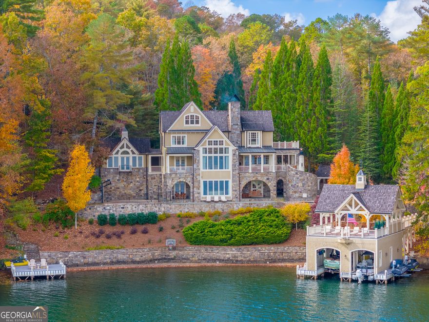 A true designer's showplace, this 5 BD, 5.5 ba Control4 Smart Home is the ultimate entertainer's retreat. Situated in a protected cove with sweeping lake and mountain views, the family room offers a vaulted ceiling, 2-story stone fireplace and  wall of windows framing wide-open lake views. Make dining a blast in this gourmet kitchen with professional appliances, a authentic juke box, a stone fireplace, dining for 10+ and access to 2 covered lakeside porches. The terrace level is equipped with a family room with fireplace, billiards, wet bar and access to a sprawling lakeside patio with built-in 10' round Jacuzzi pool, oversized fire-pit, grilling pavilion and sport court. With 3 master suites and 2 bunk-rooms, this home comfortably sleeps 23 in beds. Amenities include a gym, office, art studio, 4 indoor fireplaces and 2 outdoor fireplaces, a carport, gated entry, paved access, pre-stubbed for elevator.