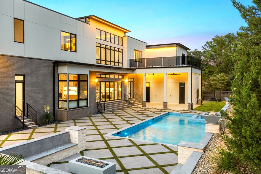A modern masterpiece of distinction, 4232 Edgewood Court is nestled on a rare 0.75-acre corner lot-one of the largest within the prestigious Indian Hills Country Club-and located in the highly sought-after Walton High School district. Offering six bedrooms, seven full baths, two half baths, and approximately 9,200 square feet across three levels, this newly completed residence pairs sculptural architecture with a full suite of resort-style amenities. From its commanding curb appeal and manicured grounds to sleek casement windows with wood-look panels and curated architectural lighting, every detail reflects thoughtful design and modern luxury. Beyond the grand pivot door, soaring ceilings frame a dramatic foyer and family room where a floating steel staircase with motion-sensor lighting becomes the architectural centerpiece. Premium chandeliers, bespoke built-ins, and a striking fireplace set an atmosphere of elegance and sophistication. The state-of-the-art kitchen blends performance and artistry with custom cabinetry, quartzite waterfall countertops, acoustic wood panels, and commercial-grade appliances. A concealed scullery ensures effortless entertaining, while sleek nano accordion doors expand the living space seamlessly to the outdoors. The main-level primary suite serves as a private retreat, complete with bespoke closets and a lavish spa bath featuring a sculptural stone soaking tub, dual vanities, and designer finishes. Upstairs, the secondary suites are equally impressive, each generously scaled with private en- suite baths. For convenience, two laundry rooms with custom cabinetry are located on both the main and upper levels. Everyday ease is further enhanced by a three-stop elevator and an expansive four-car garage. The finished terrace level lives like a private club, showcasing a temperature-controlled wine cellar, media lounge, state-of-the-art glass-enclosed gym, fully equipped sauna, powder room, and a beautifully appointed guest suite that opens to a tranquil courtyard. Outdoors, the home transforms into a private resort. A saltwater pool with integrated spa and dramatic waterfall feature anchors the backyard, complemented by a cabana, fire pit, and lush green lawns. The setting is both intimate and expansive, designed for gathering, relaxation, and year-round enjoyment. Indian Hills Country Club offers a lifestyle as remarkable as the home itself, with a 27-hole golf course, newly renovated clubhouse, eight tennis courts, and three pools-all moments from shopping, dining, parks, and both public and private schools. A rare convergence of modern architecture, curated amenities, and resort-style living-4232 Edgewood Court is more than a home, it is a private retreat in one of East Cobb's most prestigious enclaves.
