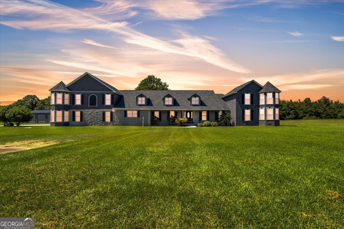 Welcome to this extraordinary Byron estate nestled on over 12 acres of private, picturesque land. From the tree-lined drive to the stately facade with twin towers, dormer windows, and a welcoming front porch, this home makes an unforgettable first impression. -Interior Living Spaces- Step inside and you're greeted by gleaming hardwood floors, wide hallways, and abundant natural light. Multiple oversized living/bonus rooms provide endless flexibility for gatherings, quiet evenings, or formal entertaining. One of the central living areas features a fireplace framed by a modern mantel, creating a cozy yet elegant focal point. Neutral tones and updated lighting throughout make the interior feel fresh, open, and ready for your personal touches. -Chef's Kitchen & Dining- The heart of the home is an expansive chef's kitchen designed to impress. Custom wood cabinetry offers incredible storage, a hideaway tv, paired with rich granite countertops and a striking butcher block island large enough for food prep and casual dining. A custom vent hood with colorful Spanish-inspired tilework adds artistry and character, while the coordinating tile backsplash wraps the space in style. Dual stainless steel refrigerators and double ovens mean you'll have more than enough room for holidays and entertaining. The kitchen is anchored by exposed wood beams, multiple chandeliers, pendant lighting, and wide windows framing views of the surrounding acreage. Adjacent to the kitchen, the oversized dining area easily accommodates a farmhouse table, making it the perfect setting for family meals or large dinner parties. A walk-in pantry with custom shelving ensures everything has its place. -Bedrooms & Baths- The primary suite is thoughtfully designed for privacy and convenience, with hardwood floors and a spa-like bath. The ensuite bathroom includes dual vanities with granite countertops, separated by a custom built-in cabinet, a soaking jacuzzi tub, and a walk-in tiled shower. Additional bedrooms are generously sized, many with hardwood flooring, large closets, and ceiling fans. Several bathrooms feature granite counters, tile showers, and double sink setups ideal for family living. -Bonus & Flex Spaces- Upstairs, an expansive bonus room spans nearly the entire width of the home complete with bar hookup - perfect for a game room, theater, or recreational hub. Bright windows, hardwood floors, and multiple ceiling fans make it a versatile space for entertaining, fitness, or large family gatherings. Additional flex rooms throughout the home can serve as offices, study areas, playrooms, or guest quarters, offering unmatched adaptability. -Outdoor Living & Amenities- The outdoor lifestyle here is unmatched. A massive screened-in back porch stretches across the rear of the home, complete with beautiful flooring and ceiling fans to keep you cool on summer evenings. From here, the property unfolds into more than 12 acres of open, manicured land, bordered by trees for privacy. Unique to this property is its full-size fenced sports court, designed to accommodate both basketball and tennis. Imagine morning workouts, weekend games with friends, or teaching your kids to play under the wide Georgia skies. Beyond the court, there's room for soccer, riding ATVs, horseback riding, or simply enjoying the peace of wide-open space. For hobbyists or those who need space for equipment, the property includes a 3-car attached garage and a large detached workshop with multiple roll-up doors. Whether you're into woodworking, classic cars, or simply need extra storage, this space delivers. -A Property That Has It All- This estate offers the rare combination of expansive indoor living, a true chef's kitchen, luxurious private suites, and one-of-a-kind outdoor amenities. It's not just a house - it's a lifestyle. Call today for showing!