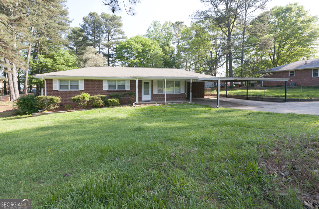 Welcome to this beautifully maintained 4-sided brick ranch offering classic charm and modern convenience. Located in a quiet, friendly neighborhood just minutes from various schools, popular shopping spots, and major highways for easy commuting. Interior Highlights: Gorgeous hardwood floors throughout + Spacious and open kitchen with generous cabinetry and prep space + Convenient utility room featuring washer/dryer, water heater, shelving, workbench, and adjoining mud room + Expansive living room perfect for relaxing or entertaining + 1.5 well-appointed bathrooms. Outdoor Features: Fully fenced backyard with level grassy area -- ideal for pets, play, or gardening + Large outbuilding/storage shed big enough for a small boat or serious tools + Inviting covered front porch and carport for sheltered parking + Long driveway offering ample additional parking. Additional Perks: Easy upkeep with durable construction + Security System In Place + Recently updated mechanical systems for peace of mind + Comfortable, affordable, and move-in ready.
