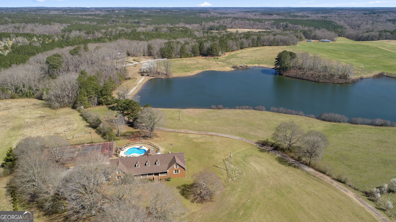 Welcome to this sprawling 8000+s/f all-brick estate! It is set on nearly 12 acres of scenic countryside with peaceful pond views. A picturesque tree-lined driveway leads you to this one-of-a-kind property, where space, comfort, and charm come together to create a true rural retreat. Inside, the warm and inviting living spaces are designed for gathering with family and friends. The main-level living room features a unique brick fireplace and a wall of windows that fill the room with natural light while showcasing the home's rich woodwork and beautiful views. The spacious kitchen is the heart of the home, offering a large island, double wall oven, and plenty of cabinet and counter space - ideal for preparing big meals or hosting get-togethers. The oversized primary suite is a peaceful haven, complete with a private bath featuring a dual vanity, soaking tub, and walk-in shower. Two additional bedrooms and two full baths are also conveniently located on the main floor. Upstairs, two expansive bonus-style bedrooms each boast private baths, along with a central living area that's perfect for a cozy hangout space, game room, or guest retreat. Downstairs, the finished basement offers even more living space with a kitchenette and a second brick fireplace - an ideal spot for family movie nights, holiday gatherings, or relaxing weekends. Outdoor living is what makes this property truly special. The brick patio overlooks a sparkling pool and spa, while the on-site tennis court provides endless entertainment. The covered front porch is the perfect place to sip your morning coffee and take in the peaceful country views. With its generous space, unique character, and serene setting, this remarkable property offers the perfect blend of comfort, charm, and country living. Don't miss the chance to make this one-of-a-kind estate your own.