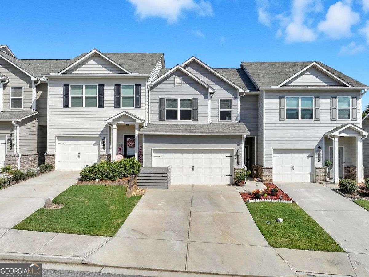 Nearly new Townhome in Oakwood not far from Lake Lanier. Walking distance to Oakwood Elementary School. Private rear yard. 2 Car garage! All bedrooms and laundry room on upper level. Kitchen with large center granite island featuring white cabinets opens to large family room with electric fireplace equipped with logs. Walk in pantry in kitchen, electric range, microwave and dishwasher. Plenty of countertop space for your chef tools! Natural light flows beautifully into main level through double windows. Powder room located in hallway to garage. Private rear patio is perfect for entertaining and grilling. Upper level is complete with spacious Owners Suite featuring a pretty trey ceiling and two closets. Owners bath has large soaking tub, double sinks, shower and leads to laundry room.... how convenient! Secondary bedrooms are generously sized and served by 2nd bath. Pride of ownership is evident in details and condition of the home.