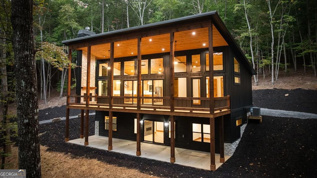 Stunning New Construction Mountain Modern on just over 4 private acres! This home offers the perfect balance of privacy, modern design, and mountain charm. From the welcoming covered porch, step into an open-concept living space with soaring windows and oversized sliders that fill the home with light and capture serene forest views. The great room centers around a sleek modern fireplace with stylish lighting, while the chef's kitchen features a 36-inch gas range, gold accents, a large island, and a spacious walk-in pantry. The dining area, framed by dramatic fixed-glass windows, creates a seamless connection to the outdoors. The main-level primary suite is a private retreat with a custom accent wall, reading sconces, walk-in closet with washer/dryer hookup, and spa-inspired bath with dual vanities and a striking tiled shower. Just outside, a covered porch with a wood-burning fireplace invites you to relax and soak in the peaceful setting. A half bath completes the main level. Downstairs, the terrace level offers even more space to entertain with a cozy gas-log fireplace, wet bar with wine cooler, and storage under the stairs. Two guest bedrooms (one with en suite), a bunk room, and a third full bath with tiled tub surround provide plenty of room for family and friends. The lower-level patio is ideal for a hot tub or outdoor lounge. With usable acreage, and ample parking, this home is as functional as it is stylish. Whether you're looking for a luxury rental investment or a private mountain escape, this property delivers it all.