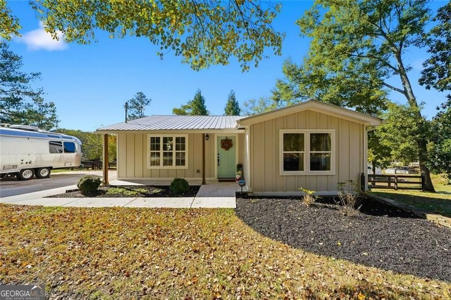 Step inside this thoughtfully rebuilt ranch and enjoy single-level living with smart, stylish finishes throughout, all set on a spacious half-acre lot with a metal roof and modern curb appeal. At the heart of the home, the open-concept living area is bright and welcoming, centered around a custom kitchen designed for both ease and style. Premium white Carrera marble countertops (with lifetime warranty), open shelving, tile backsplash, and soft-close cabinetry frame stainless steel GE appliances. A deep pantry, farmhouse light fixtures, and a breakfast bar create space to prep, gather, and unwind. Real hardwood floors run throughout, while recessed LED lighting and Lutron dimmer switches in the main living areas and bedrooms give you full control over the ambiance. The primary bedroom feels like a private retreat with its shiplap accent wall and French doors leading to the oversized back deck, recently stained with IR-reflective stain and now with added stairs for easy backyard access. The en suite bathroom features a walk-in shower with new glass enclosure, marble counters, dual sinks, and a sliding barn door. The second bedroom is light-filled and close to a hall bath with a full tub and sleek tile finishes. Out back, the large fenced yard offers privacy and plenty of room to garden, host, or recharge. A new stone retaining wall adds structure near the end of the driveway, and the walk-in crawlspace gives you dry, covered storage. There's also a large shed, and room to park an RV. Additional features include a 2021 water heater and septic tank cap, SimpliSafe home security system with doorbell cam and keypad lock, spray foam attic insulation, and a termite plan with Sentricon bait stations. Trees and debris have been cleared for cleaner lines and better use of space. Taken down to the studs and fully rebuilt in 2020, this home is move-in ready and made for living.