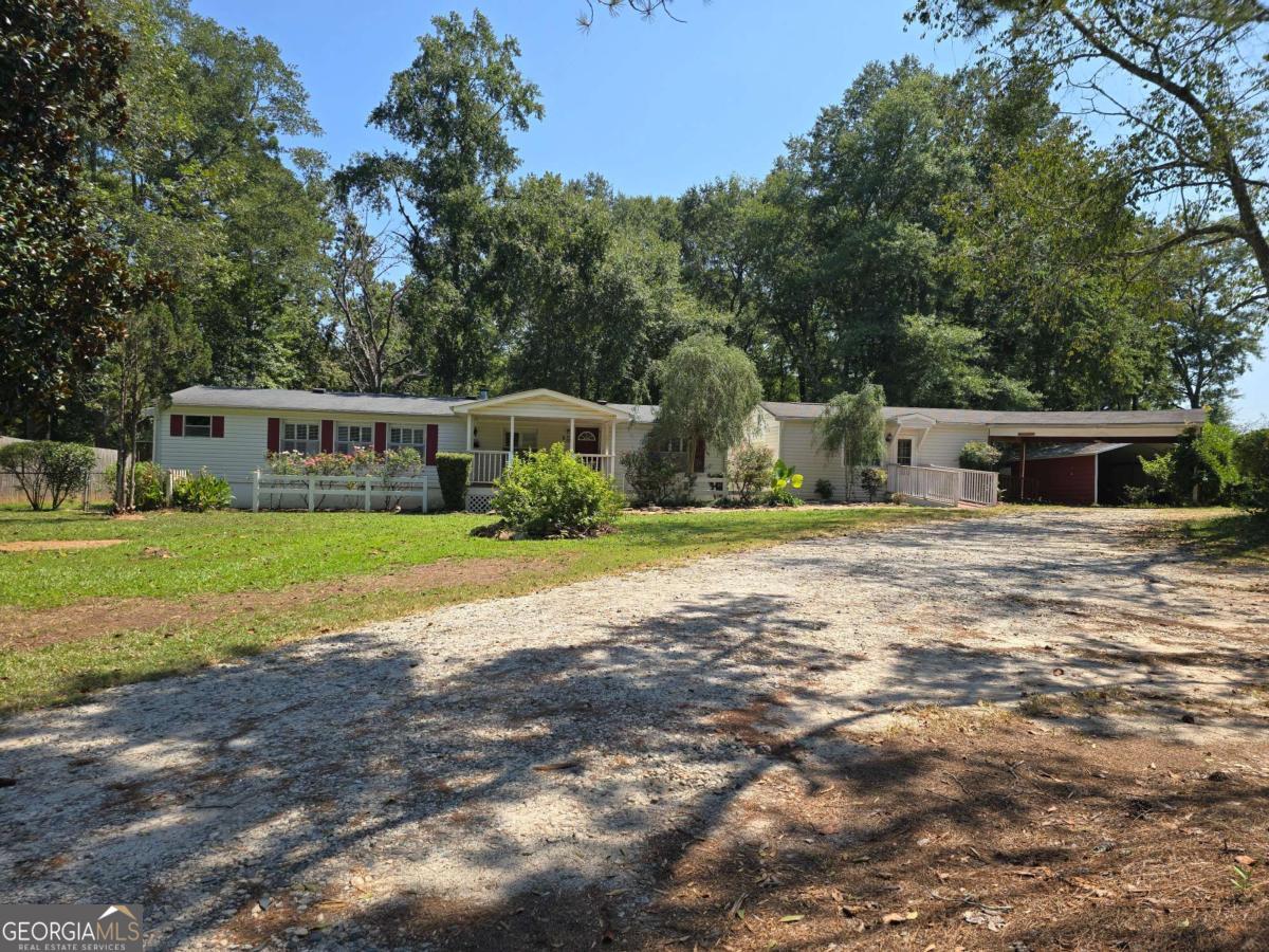 Gated, single-level manufactured home on 8.43 acres. A private drive opens to a well-manicured front yard, with multiple storage buildings and sheds spread across the property-ideal for tools, equipment, toys, and on-site workspace. Inside, the home's single-story layout keeps life easy. Wheelchair accessible entrance, open living/dining flow, comfortable bedrooms, and simple access to the outdoor areas. Covered back patio is perfect for entertaining or having your morning cup of coffee. Schedule your tour today!