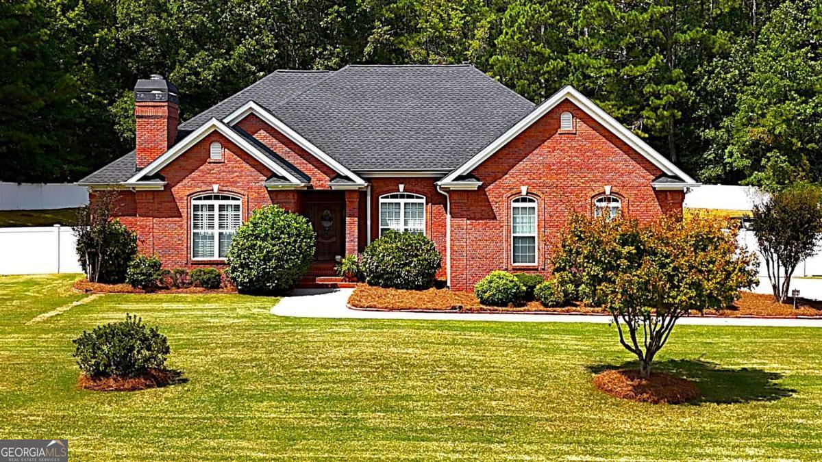 Absolutely stunning 4 bedroom 2 and half bathroom four side brick ranch home with an incredible yard!  Located in the established popular Mallard Lake neighborhood this is the one!  Home is immaculate, well maintained, level lot, huge fenced back yard with an incredible covered porch....look no further!  Open the front door to this stepless ranch to gleaming hardwoods in all of the common areas and take note of the beautifully crafted custom trim work and molding throughout this home !  To the right the formal dining room with its incredible craftsman trim accent wall is the perfect spot for family dinners or holiday gatherings.  The cozy family room is located to the left and is anchored by the gas brick fireplace, with white mantle and ship lap trim all the way up to the soaring vaulted ceilings! The owner's suite is located down the hall to the left of the entry way in this split bedroom plan.  The trim detail in this master is incredible, trey ceilings, crown molding, with exterior door to the outside living areas!  The custom master bathroom features a soaking tub, tiled/glass shower, double vanities and water closet; again, the trim work with lawyers panel is repeated in this bright sunny bathroom.  The 3 secondary bedrooms are all located on the other end of the home and are all good-sized sharing a full bath and are adjacent to the laundry room and the half bath.   Natural light floods the bright airy kitchen, which features white custom cabinets, granite counter tops, tile backsplash, and gleaming stainless-steel appliances.  Always the "heart of the home" this kitchen is certainly that, with an island that seats two and nice sized breakfast area which can support a full size kitchen table this will be the spot for casual family meals.  From the kitchen sink keep an eye on the kids as they play in the back yard or check on your guest out on the incredible covered back porch!  Walk out the glass back door to this phenomenal outdoor living space!  Spend those fall Saturday evenings watching the game out on this incredible covered porch, with the custom stained wood tongue and groove vaulted ceiling, stacked stone columns, ceiling fan, wall mount TV hookup,  all looking out over this enormous fully fenced yard! This home is absolutely move in ready and is perfect for not only a growing family with the 4 bedrooms, 1 acre lot and almost half acre of the yard fenced; its also perfect for seniors with only a couple of steps to get in the home, low maintenance brick and vinyl/pvc exterior trims and fence.  The quiet Mallard Lake Community has only 1 main street, which winds around the almost 30 acre lake, has beautiful homes with manicured lawns and is very convenient to both Villa Rica and Carrollton!