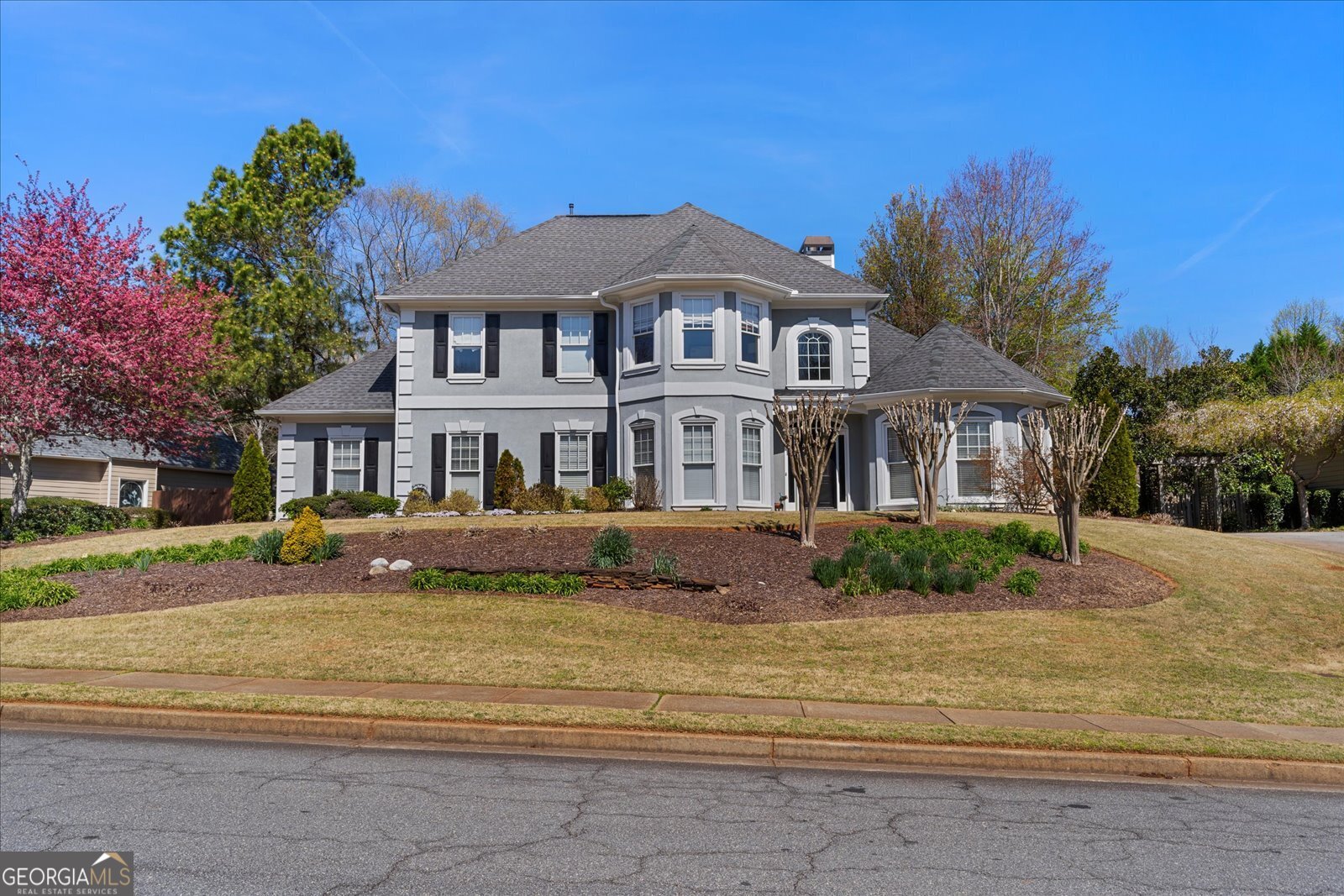 Welcome to this stunning master-on-main home with a flat, fenced backyard in the heart of Milton's most sought-after location. Perfectly situated near Crabapple Crossing Elementary, Northwestern Middle, and Milton High School, and just minutes to shops, dining, and community events, this home blends lifestyle and convenience. Inside, you'll find 4 bedrooms and 2.5 baths designed for both comfort and style. The main-level primary suite features a spa-like bath and a spacious walk-in closet with custom built-ins. The cathedral-ceiling great room is filled with natural light and centered around a cozy fireplace with views of the private backyard retreat. The formal living room offers the perfect flex space for a home office, while the separate dining room is ideal for gatherings. The bright, open kitchen shines with granite countertops and stainless steel appliances. A large walk-in laundry/mudroom adds everyday convenience. Upstairs, you'll find three generously sized bedrooms and an oversized guest bath that could easily be converted to two full baths. Updates include new carpet on the main level. The home's hardcoat stucco exterior and side-entry two-car garage add both curb appeal and functionality. Located in an active swim/tennis neighborhood with frequent social events, this home offers the ideal combination of community, comfort, and location.