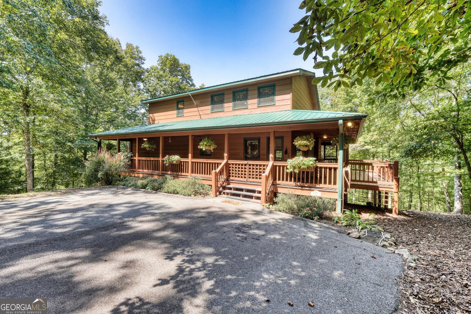 Creekfront Cabin-Style Retreat - Perfect for Full-Time Living or Vacation Rental! This charming quality-built 3 bedroom, 3 bathroom cabin-style home offers the perfect blend of rustic charm and modern comfort, making it an ideal private retreat or a fantastic investment opportunity. Nestled in a serene, secluded setting yet conveniently close to shopping, this property provides the best of both worlds. Step inside to an open-concept living room with soaring cathedral ceilings and a striking rock gas fireplace, creating a warm and inviting atmosphere. The kitchen is a chef's dream, featuring a granite-topped island, ample cabinetry, and included appliances. On the main level, you'll find a master suite with a spa-like bathroom complete with heated floors, a step-in shower, and a walk-in closet. Another master suite upstairs offers a private bath with double sinks and its own walk-in closet. The upper level also includes a spacious open loft area-perfect for a home office, playroom, or additional living space. The walkout basement expands the living area with a bedroom, full bath, game room or living area, and a large screened-in porch overlooking the creek. A sizable storage room with a utility sink provides plenty of functionality. Enjoy the outdoors on the expansive wraparound deck, designed with open grilling areas, a wired and supported space for a hot tub, and peaceful views of the creek. Enjoy evening gatherings with friends and family around the large fire pit area. Store your tools and toys in the 14x16 double-door storage shed. The asphalt driveway, low-maintenance yard, and timeless wood-sided cabin exterior add to the property's appeal. With two master suites, multiple living areas, and thoughtful details throughout, this home is a versatile, turnkey retreat ready to be enjoyed or shared as a vacation rental.