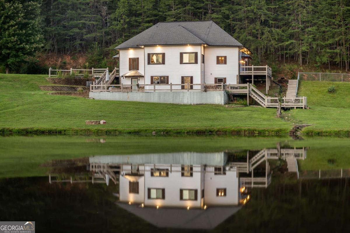 Tucked away on 3.25 private acres in the heart of Mineral Bluff, this stunning mountain retreat combines rustic elegance with modern comfort, offering space, serenity, and style in every corner. Surrounded by peaceful seasonal mountain views and lush natural beauty, the home spans over 3,800 square feet across multiple levels, featuring rich hardwood floors, soaring cathedral ceilings, and an inviting, open layout perfect for both everyday living and entertaining. The main level welcomes you with a cozy living room and gas fireplace, a beautifully designed kitchen with granite countertops and stainless steel appliances, and seamless flow into the dining and great rooms. Two spacious bedrooms on the main floor each feature ensuite baths with walk-in showers, while a half bath adds convenience for guests. Upstairs, two additional bedrooms with charming dormer windows share a full bath, and a large loft provides flexible space for relaxing, reading, or working from home. The fully finished basement offers a second kitchen, laundry area, comfortable living room with fireplace, bonus room ideal for an office or studio, and another full bath with access to a private patio. Additional features include laundry on both main and lower levels, a detached workshop and storage building, fenced dog area, a welcoming front porch, and a large back deck for soaking in the peace and quiet. This home is designed for both comfort and functionality. From morning coffee on the deck to quiet evenings by the fire, this mountain home offers an exceptional lifestyle in a truly special setting-where luxury meets nature, and every corner invites you to slow down and stay awhile.