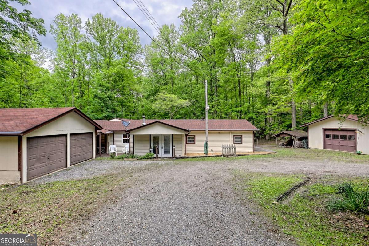 Welcome to this charming mountain retreat nestled on a generous 0.96-acre lot. This 2-bedroom, 2-bathroom home features a large family room with a wood-burning stove, a generously sized kitchen, dining area, flex room, and partially unfinished basement with a utility sink and additional laundry connection. Each bedroom is equipped with its own private bath, enhancing the practicality and appeal of this layout. Step outside to enjoy the peaceful surroundings from the screened porch overlooking a private backyard with a small creek. The property also features a detached 2-car garage, a sizable outbuilding/workshop, both equipped with power, ideal for storage or hobby pursuits. With no HOA and no restrictions, you have the freedom to truly make this property your own. Don't miss out on this amazing opportunity to secure a great value for your future home!
