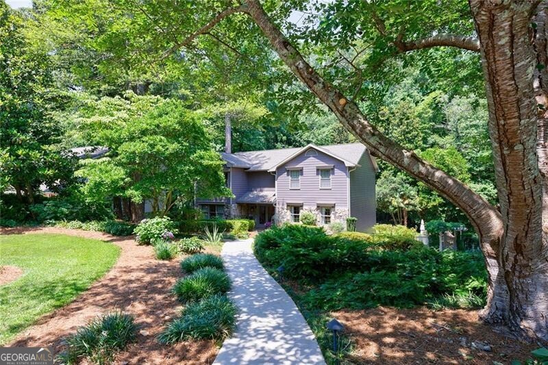 This impeccably maintained home offers a harmonious blend of sophistication and modern convenience in one of Marietta's most sought-after neighborhoods. A grand entrance welcomes you with custom iron stair railings and handcrafted lighting, setting the tone for thoughtful touches throughout. The chef's kitchen showcases premium stainless appliances, a 6-burner gas range with griddle, and a Sub-Zero stainless steel refrigerator. Custom cabinetry with pull-out storage and an additional pantry ensure effortless organization. A sunlit keeping room, framed by a stunning arched picture window and fully operable casement windows, provides an inviting space for guests and family. The expanded living room, enriched by custom wood built-ins and a gas log fireplace, offers a refined yet comfortable space for gatherings. Soft LED dimmers and fixtures enhance both ambiance and efficiency. The formal dining room, illuminated by a Schonbek chandelier and sconces, exudes timeless elegance, while the powder room makes a statement with an antique marble vanity and copper vessel sink. Real hardwood floors span the entire main level. The upper-level primary suite is a sanctuary of comfort, featuring newly installed premium carpet, automated blackout shades, a ceiling fan, light dimmers with remotes, and a smart thermostat. The spa-inspired ensuite bath is a masterpiece, adorned with Italian tile, a high-flow rainfall shower with steam, a separate whirlpool garden tub, and a private water closet. Dual vanities with glass vessel sinks, a sparkling crystal chandelier, a stained-glass window, and French doors elevate the space to a retreat. A custom walk-in closet provides ample storage with built-in drawers and shoe racks rare for this period home. The secondary bedrooms offer ceiling fans, extra closet storage, and easy access to a well-appointed hall bathroom featuring a whirlpool tub with a European shower. The laundry room conveniently shares the same upstairs hallway. The terrace level is a versatile haven, boasting oversized porcelain tile flooring, and a thoughtfully designed in-law suite with a private entrance, wired for a potential second kitchen adjacent to the outdoor patio. A full bath with a walk-in shower completes the suite. Additional living areas include a dedicated office or media room and a cedar-lined closet with custom shelving separated by elegant French doors. Step outside to a private, resort-style retreat where lush landscaping, professional lighting, and an enchanting fountain create a serene ambiance. A sparkling saltwater pool, luxury whirlpool spa with cascading waterfall, and a pergola-framed privacy gate make this outdoor sanctuary ideal for relaxation and entertaining. Two secure storage rooms provide space for seasonal furniture and pool accessories, while the wireless pool control system and new pool pump offer worry-free enjoyment. An outdoor prep sink completes the grilling area and a hot-cold mixing faucet makes a perfect pet wash. The home's exterior has been freshly painted (2023), and the roof was replaced in 2022, ensuring long-term peace of mind. The two-car garage features insulated ultra-quiet doors, remote and keypad entry, and an electric vehicle charging station. An endless supply of hot water via tankless water heater serves the upstairs baths, supplemented by a 50-gallon water heater installed in 2019. Located in the prestigious Walton High, Dickerson Middle, and Mount Bethel Elementary school district, this exceptional residence is a rare opportunity to own an elegant, amenity-rich home in a premier location. Experience the perfect blend of luxury, modern technology, and timeless design.