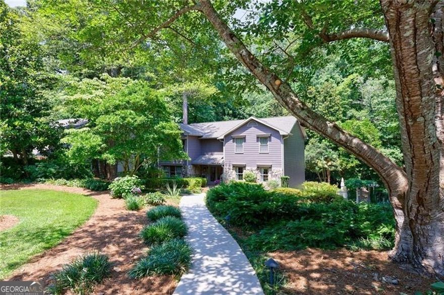 This impeccably maintained home offers a harmonious blend of sophistication and modern convenience in one of Marietta's most sought-after neighborhoods. A grand entrance welcomes you with custom iron stair railings and handcrafted lighting, setting the tone for thoughtful touches throughout. The chef's kitchen showcases premium stainless appliances, a 6-burner gas range with griddle, and a Sub-Zero stainless steel refrigerator. Custom cabinetry with pull-out storage and an additional pantry ensure effortless organization. A sunlit keeping room, framed by a stunning arched picture window and fully operable casement windows, provides an inviting space for guests and family. The expanded living room, enriched by custom wood built-ins and a gas log fireplace, offers a refined yet comfortable space for gatherings. Soft LED dimmers and fixtures enhance both ambiance and efficiency. The formal dining room, illuminated by a Schonbek chandelier and sconces, exudes timeless elegance, while the powder room makes a statement with an antique marble vanity and copper vessel sink. Real hardwood floors span the entire main level. The upper-level primary suite is a sanctuary of comfort, featuring newly installed premium carpet, automated blackout shades, a ceiling fan, light dimmers with remotes, and a smart thermostat. The spa-inspired ensuite bath is a masterpiece, adorned with Italian tile, a high-flow rainfall shower with steam, a separate whirlpool garden tub, and a private water closet. Dual vanities with glass vessel sinks, a sparkling crystal chandelier, a stained-glass window, and French doors elevate the space to a retreat. A custom walk-in closet provides ample storage with built-in drawers and shoe racks rare for this period home. The secondary bedrooms offer ceiling fans, extra closet storage, and easy access to a well-appointed hall bathroom featuring a whirlpool tub with a European shower. The laundry room conveniently shares the same upstairs hallway.  The terrace level is a versatile haven, boasting oversized porcelain tile flooring, and a thoughtfully designed in-law suite with a private entrance, wired for a potential second kitchen adjacent to the outdoor patio. A full bath with a walk-in shower completes the suite. Additional living areas include a dedicated office or media room and a cedar-lined closet with custom shelving separated by elegant French doors. Step outside to a private, resort-style retreat where lush landscaping, professional lighting, and an enchanting fountain create a serene ambiance. A sparkling saltwater pool, luxury whirlpool spa with cascading waterfall, and a pergola-framed privacy gate make this outdoor sanctuary ideal for relaxation and entertaining. Two secure storage rooms provide space for seasonal furniture and pool accessories, while the wireless pool control system and new pool pump offer worry-free enjoyment. An outdoor prep sink completes the grilling area and a hot-cold mixing faucet makes a perfect pet wash. The home's exterior has been freshly painted (2023), and the roof was replaced in 2022, ensuring long-term peace of mind. The two-car garage features insulated ultra-quiet doors, remote and keypad entry, and an electric vehicle charging station. An endless supply of hot water via tankless water heater serves the upstairs baths, supplemented by a 50-gallon water heater installed in 2019.  Located in the prestigious Walton High, Dickerson Middle, and Mount Bethel Elementary school district, this exceptional residence is a rare opportunity to own an elegant, amenity-rich home in a premier location. Experience the perfect blend of luxury, modern technology, and timeless design.