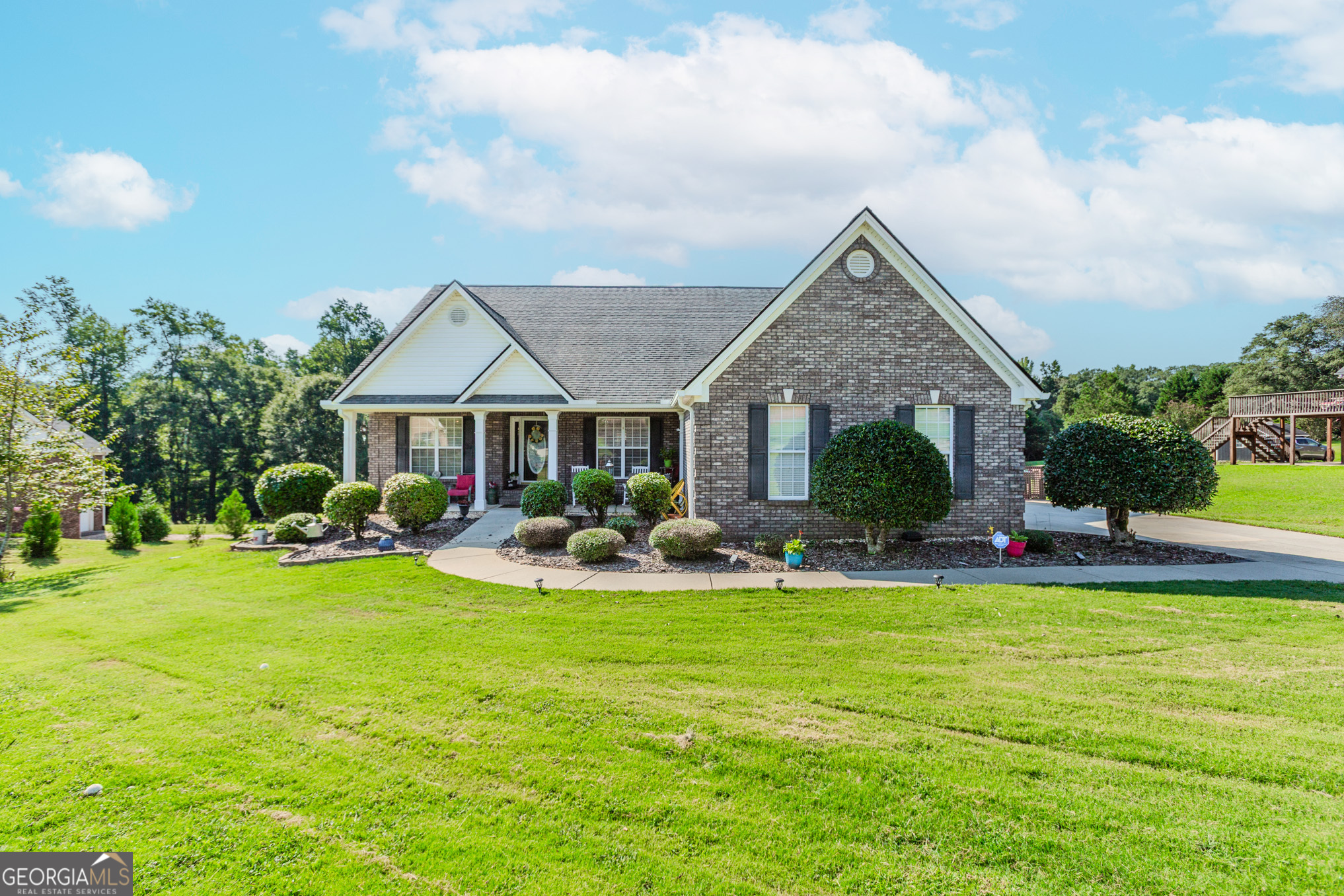 Well-maintained 4-sided brick ranch with a full, unfinished basement on 1.3 acres. Home offers 3 bedrooms, 2 full baths, and an open floor plan with high ceilings. Hardwood floors throughout main living areas. Spacious family room with fireplace and adjoining sunroom. Kitchen features white cabinetry and a breakfast area. Separate dining area. Master on main with tray ceiling, walk-in closet, dual vanities, separate tub and shower, and private water closet. Secondary bedrooms are spacious with ample closet space. Laundry room on main. Basement is full size, unfinished, and studded for bath. Exterior features include covered front porch, back deck and patio, storage shed, and large open backyard with creek at rear of property. Solar panels installed. Peach tree in front yard. Quiet, established neighborhood. Built in 2003. Septic system.
