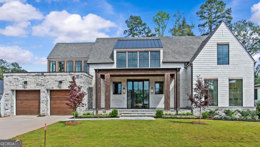 LAKE TAHOE INSPIRED NEW CONSTRUCTION HOME IN RICHLAND POINTE VILLAGE STEPS FROM THE WATER AND RESORT STYLE AMENITIES, THIS LAKEFRONT HOME HAS IT ALL. This move in ready custom home offers an exceptional lakefront lifestyle in Reynolds Lake Oconee and is the only lakefront home with a private max dock currently available in Richland Pointe Village. Designed by Norwood Architects and built by DreamBuilt, this 5 bedroom, 5 and a half bath home spans three levels with stunning lake views from nearly every room. An expansive front porch with stone floors and custom cedar columns creates a warm welcome. A 10 foot custom metal and glass front door opens to bright, airy interiors. Just beyond the foyer, the great room impresses with soaring two story Marvin specialty windows framing lake views, vaulted ceilings with wood beam accents, white oak floors, and a limestone fireplace with stone cast mantle. Flowing from the great room, the chef's kitchen features quartzite countertops and backsplash, an eat in island, custom vent hood, Bell custom cabinetry, and top tier panel ready appliances including Wolf, SubZero, and Cove. A wet bar with under counter wine cooler and space for a coffee station, plus a walk-in pantry with appliance garage, complete the space. The covered patio off the great room includes a built in outdoor kitchen with grill, prep counter, and beverage cooler, perfect for al fresco dining. The main level also offers a spacious guest/primary suite, ideal for single level living. A built in mudroom, laundry room, powder room, and framed shaft for a future elevator add convenience. Upstairs, two lake facing bedrooms open to private covered balconies and feature angled Marvin windows, en suite baths, and custom Artisan closets. One functions as a luxurious secondary primary suite. A spacious flex area at the landing allows for a sitting area, library, home office, or lounge. The terrace level is made for entertaining with a full bar, SubZero beverage center and ice maker, wine cellar rough in, and a second laundry. Two additional bedrooms with full baths complete the lower level. Hartstone decking surrounds the pool and spa, with low maintenance turf providing year round greenery. A stone aggregate path leads to the private max dock. The Brava synthetic cedar roof, Texas limestone and cedar shingle exterior, designer lighting, built in speakers, and extensive millwork reflect the home's quality and craftsmanship. Membership Available.