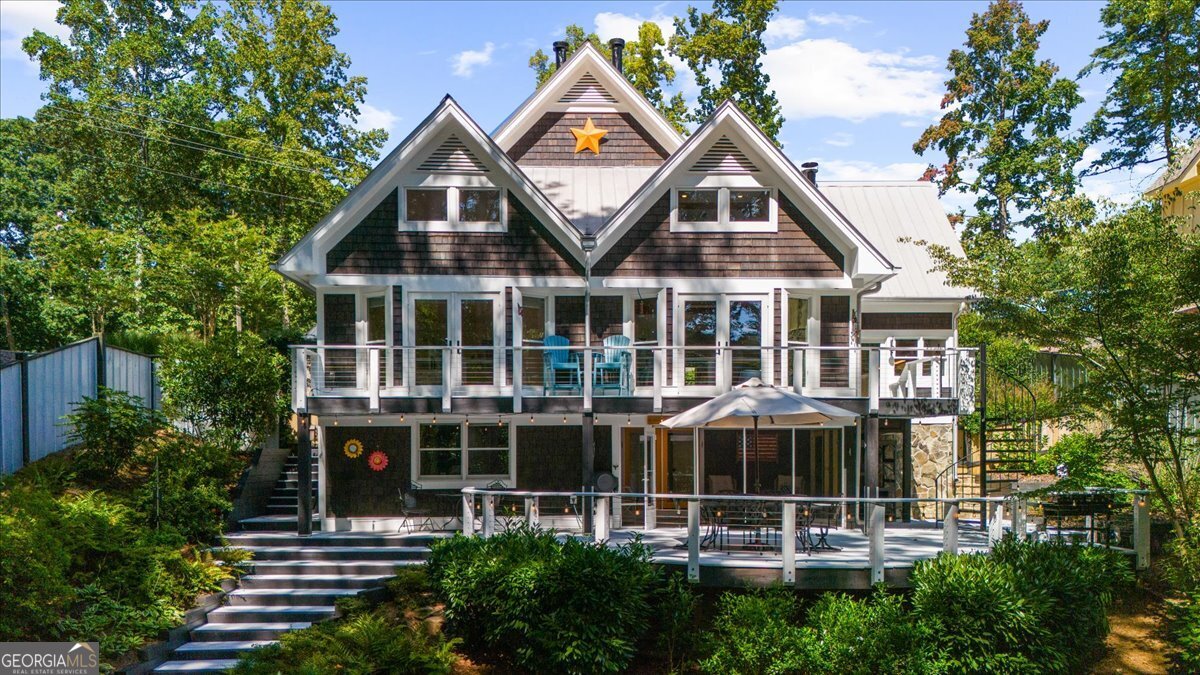 Who wants to live on the south-end of the lake that is about as close to Atlanta as you can get? Have you been searching for 'the perfect' lake home that you would LOVE everytime you walk in the front door and would be proud to entertain family and guests? This isn't just a home, it is a super-unique, fully renovated sanctuary that blends rustic charm with modern luxury, year round views of the lake and an easy walk to the dock. With over $250,000 in renovations in the past 3 years, the sellers have lovingly updated and maintained the entire home, from top to bottom. From the moment you arrive, you'll be amazed by the beautiful character of the wood shingle exterior and the elegant presence of the metal roof. Once inside, the heart pine flooring, custom built-ins, mantles and trim, designed from reclaimed barnwood, beamed ceilings and 3 cozy fireplaces makes this the perfect home to enjoy all 4 seasons. The gourmet kitchen is a chef's dream with high end appliances and an eat-in area that opens directly onto the deck. There is a charming wet bar/coffee bar with an additional full refrigerator that ensures you will always be ready to entertain, whether you are serving morning brews or evening cocktails. The main level primary suite is like a private oasis, complete with a fireplace, a spa-like bath and huge, custom closet will make you feel like you're in a high-end boutique. This impressive multi-level home has a gorgeous suite on the upper level and an equally impressive suite on the lower level. The lower level flex room is perfect for a bunk room, exercise room or a 2nd home office. Do you work from home? The bright, large office on the main level is the perfect area to get a bit of work done before heading out on the lake, and overlooks the koi pond. The open dining room blends with the great room and makes this a great area for conversation and entertaining. Step outside to the massive deck to enjoy the great outdoors or head down to the newly built screened porch on the lower level. There are so many interesting areas to spend time with a group or get away from it all in a quieter area of the home. The massive, cleared side lot is a highly sought-after bonus, offering a blank canvas for a future 2 car garage, home expansion or simply providing ample parking for a boat, trailer or RV. Stroll down to the lake, with beautiful water and new riprap at the shoreline for erosion control, to your dock with a party deck and boat lift. Take off in your boat to explore the marinas with lakeside dining or having a blast at Margaritaville at Lake Lanier Islands, all just a short boat ride away. This more than just a home, it's an invitation to a life of fun, luxury and serenity on Lake Lanier!