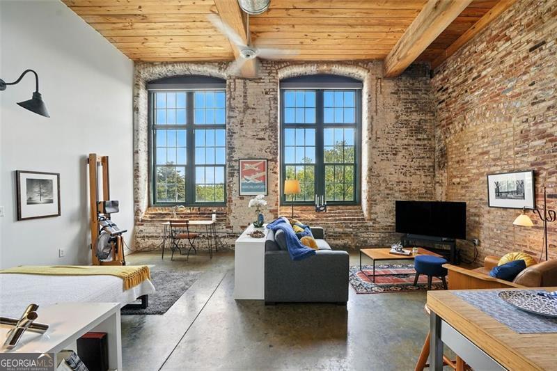 Own this RARE corner condo in The Stacks! Formerly an 1800s cotton mill, this property is located only a few minutes walk to Krog Street Market, Eastside Beltline Trail, and the new Krog District. Walk right outside to the vibrancy of Carroll Street. The Stacks is centrally located with easy access to I-75, I-85 and I-20 making the morning commute a breeze. Better yet, skip the commute and work from home with upgraded Fiber Internet! The Stacks offers premier luxury loft residences boasting all the amenities! Two Rooftop decks, State-of-the-Art Fitness Center, Olympic-size Swimming Pool, Dog Runs, and Charming Outdoor Entertaining Areas just a few steps from renowned restaurants and nightlife. This immaculate and spacious studio blends historic charm and modern living with soaring 15-foot ceilings, 2 story east-facing windows, exposed brick walls, and kitchen and bathroom. Exceptional storage in the walk-in closet, dressing room, and immense utility room, as well as access to additional space above the main floor. This highly desirable and unique unit has only one shared wall. Nothing to do here! Just move right in and start enjoying this gem and your fantastic life at one of Atlanta's most coveted communities, The Stacks!