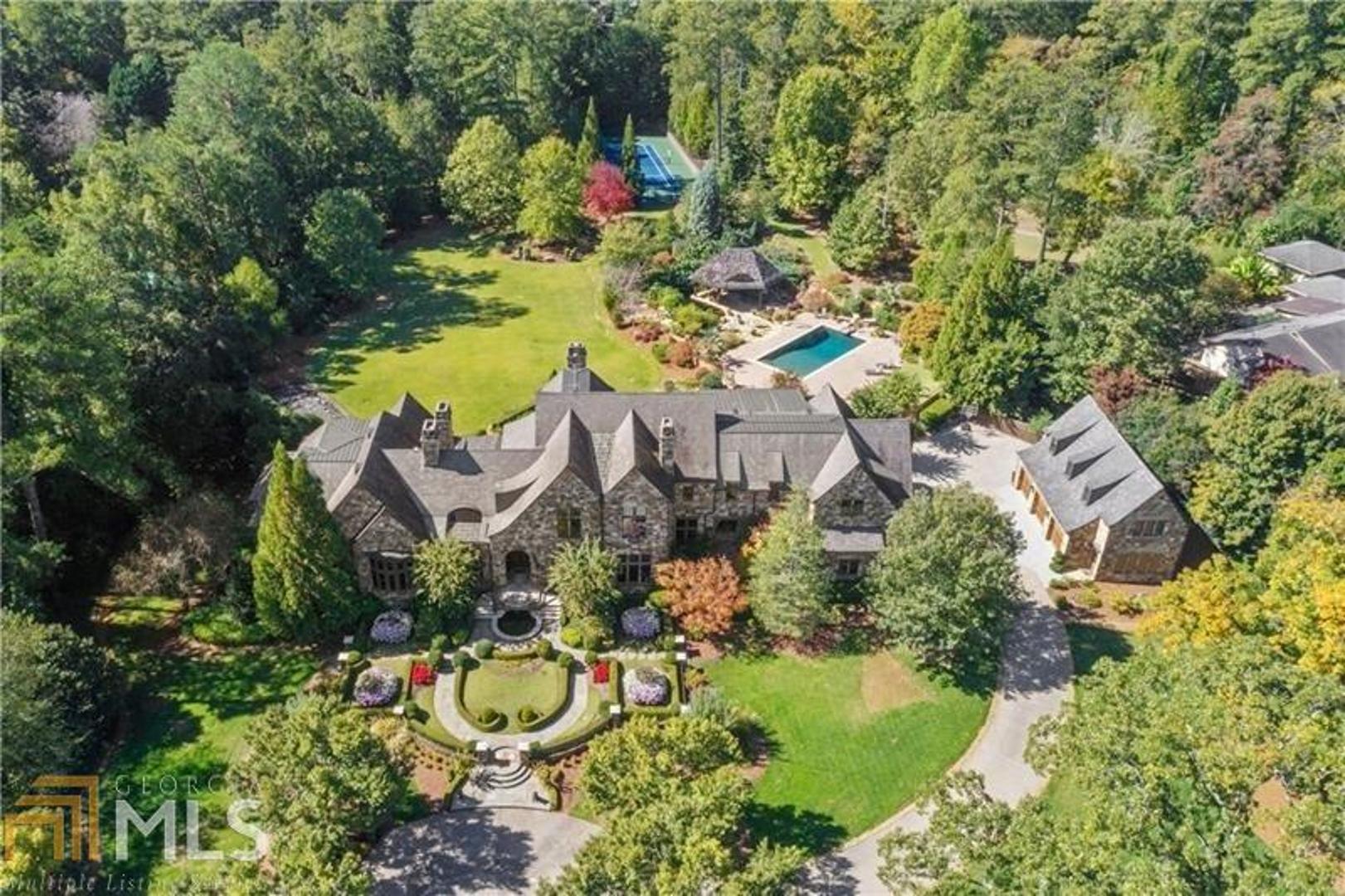 Spectacular gated estate beautifully perched on 4.2 perfectly flat acres in the heart of Sandy Springs. The picturesque grounds feature formal and informal gardens, Koi ponds, pool, pool pavilion, lighted tennis court, and one of the largest lawns you will find in Atlanta. Four-sides stone manor offering an abundance of living & entertaining spaces. The main level offers an oversized kitchen with double islands, grand fireside keeping room, formal living room, formal dining room, library, study, and oversized master-on-main featuring a sitting room, large closets, and spa bathroom. Upstairs consists of four ensuite bedrooms, including a secondary master suite with adjoining sitting room, and bonus room. Full finished basement offers a gym, recreation room, billiards room, temperature-controlled wine cellar and kitchenette. The guest house features an additional bedroom suite, living room, and powder room. Additional features include 6-car garage, his/her pool bathrooms, slate roof, completely gated/fenced estate offering complete privacy and security.