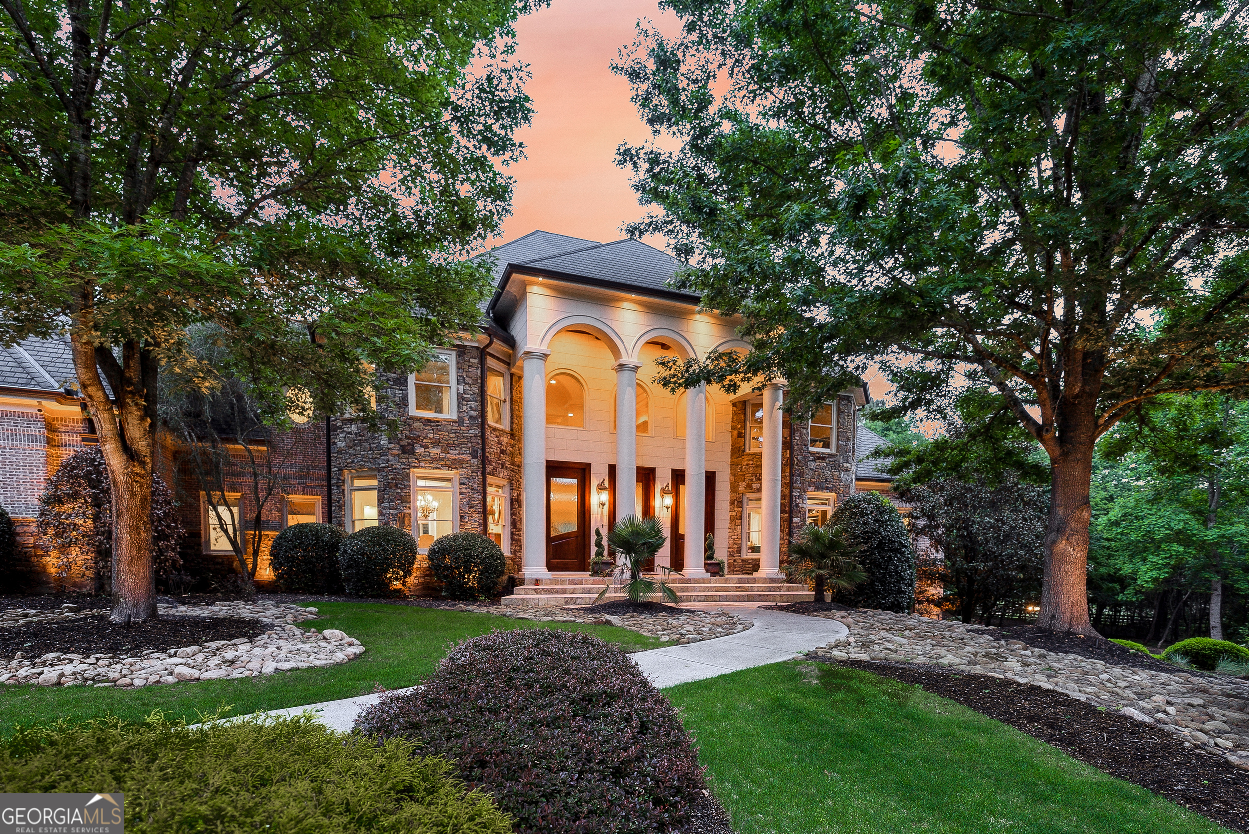 Tucked inside The Paddocks, a quiet enclave of luxury estates, 110 Ryan Lake Trail is a privately gated lakefront residence offering over 14,000 square feet of refined living space on 3.8 acres in Alpharetta-perfectly positioned on the Cherokee County side for the benefit of lower property taxes while remaining close to all that Milton and Alpharetta have to offer. Designed for both grand entertaining and comfortable everyday living, this impressive privately gated residence features six bedrooms plus a large flex room currently used as a seventh bedroom, seven full bathrooms, three half bathrooms, and a total of six garage spaces. The home's well-planned interior layout includes expansive living areas across all three levels, multiple bedroom suites, and a thoughtful blend of formal and casual spaces to suit a variety of lifestyles. A grand two-story foyer with a timeless wrought-iron curved staircase opens to a spacious great room with soaring ceilings and a fireplace, creating a central gathering space for the home. The kitchen is designed for entertaining, with a large center island, Thermador and SubZero appliances, walk-in pantry, and a separate catering kitchen with private garage access-ideal for hosting events or large parties. The layout flows into a fireside keeping room and breakfast area, as well as a summer kitchen and living space with vaulted tongue-and-groove ceiling, grilling station, and dual dishwashers for convenient indoor-outdoor living. The main-level primary suite offers a private retreat with a morning bar, fireside sitting area, private balcony, spa-inspired bathroom, and an oversized custom walk-in closet with central island. The main level also includes a formal study, formal dining room, mudroom with built-ins, two guest powder rooms, and sizable laundry room. Upstairs, a second primary suite with Juliet balcony is accompanied by two additional ensuite bedrooms, a fourth bedroom with hall bath, secondary laundry room, and a large bonus room that can serve as a playroom, media room, or seventh bedroom. The finished terrace level is designed for recreation and relaxation, featuring a home theater, game room, sauna, custom fitness gym and golf simulator, full bar, wine cellar, guest ensuite, and an additional bathroom. It opens directly to the backyard and the property's private lake frontage, offering a peaceful setting for quiet outdoor enjoyment. Additional highlights include a whole-home audio system, Vantage lighting controls, LeafGuard gutters, and a dedicated sump system. The grounds are professionally landscaped and include a full sprinkler system and outdoor lighting throughout. With four garages on the main level and two on the terrace level, the property is well-suited for car collectors, multigenerational living, or extra storage. The private lake offers a unique and serene outdoor amenity for non-motorized recreation or simply enjoying nature. Zoned for sought-after Creekview High School and minutes from top local attractions, the home is just 5 minutes to Milton's Mini Publix, 7 Acre Barn Grill, and Scottsdale Farms, 15 minutes to the shops and restaurants of Downtown Crabapple, and 20 minutes to GA-400, Avalon, and Halcyon. Additional 3 acres available for $650,000